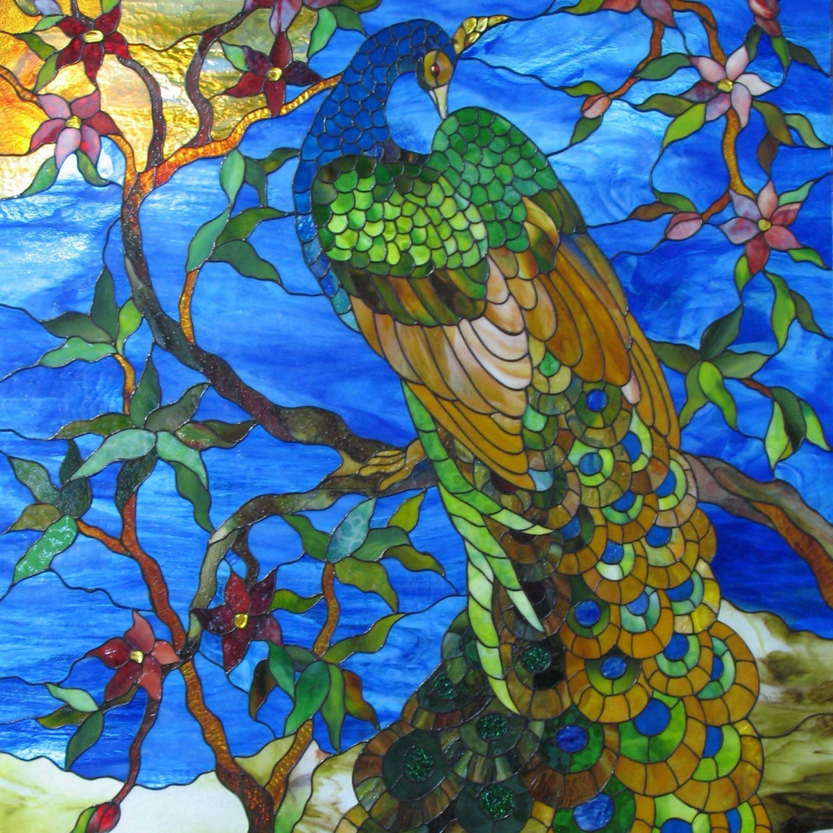 Blue stained glass peacock perched on a branch among blossoms