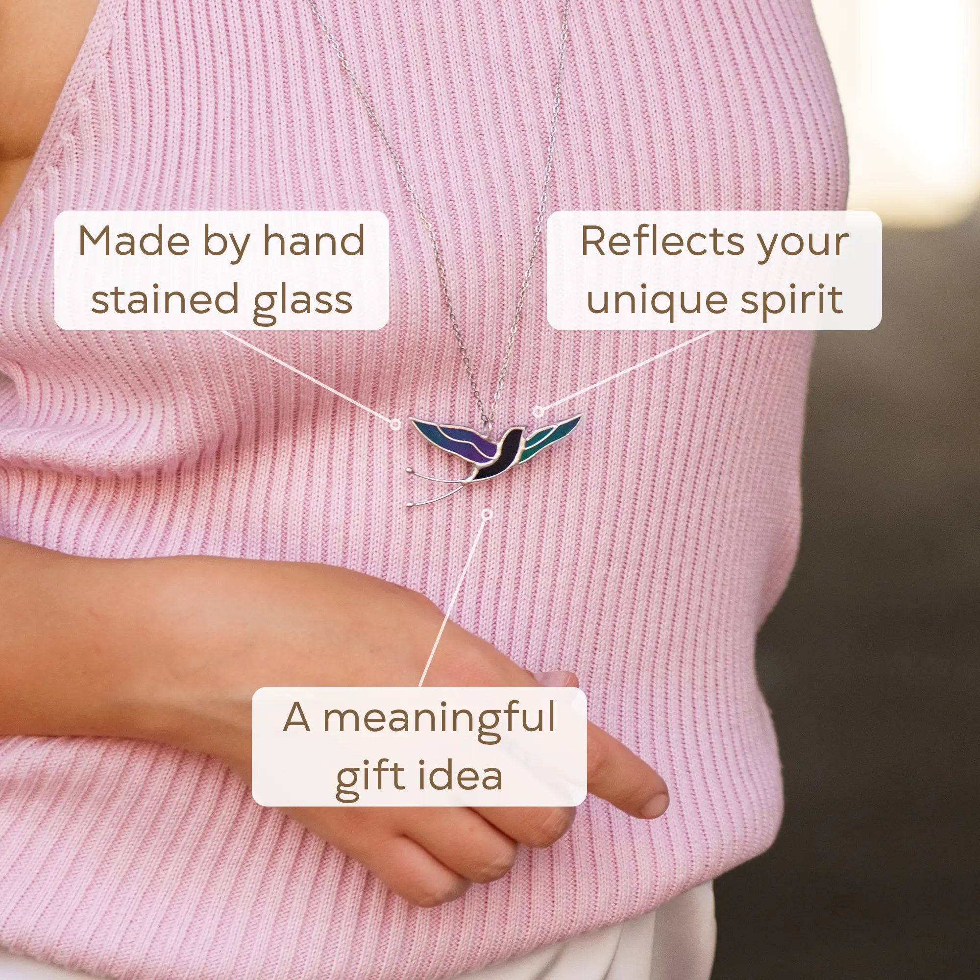 Close-up of the handmade stained glass swallow pendant - an iridescent bird in flight with wings spread, on a delicate silver chain, a meaningful gift for bird lovers