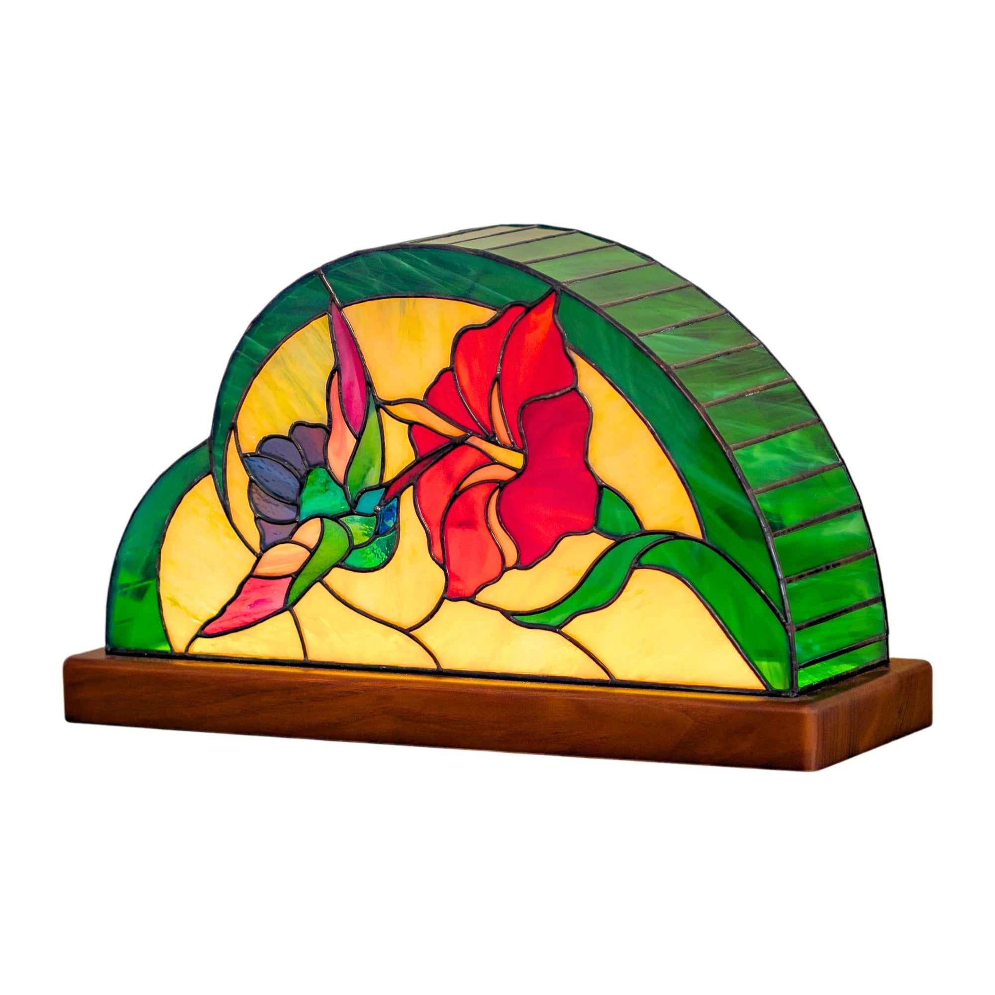 Handmade Tiffany-style stained glass table lamp on a wooden base showing a hummingbird sipping from a red hibiscus among green leaves - hand-cut stained glass home decor on a white background