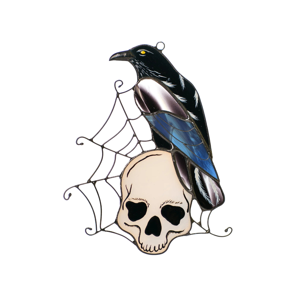 Handmade stained glass raven suncatcher on a white background, glossy black raven with an iridescent blue and lilac wing perched on a bone-white skull in a wire spider web - gothic Halloween window decor