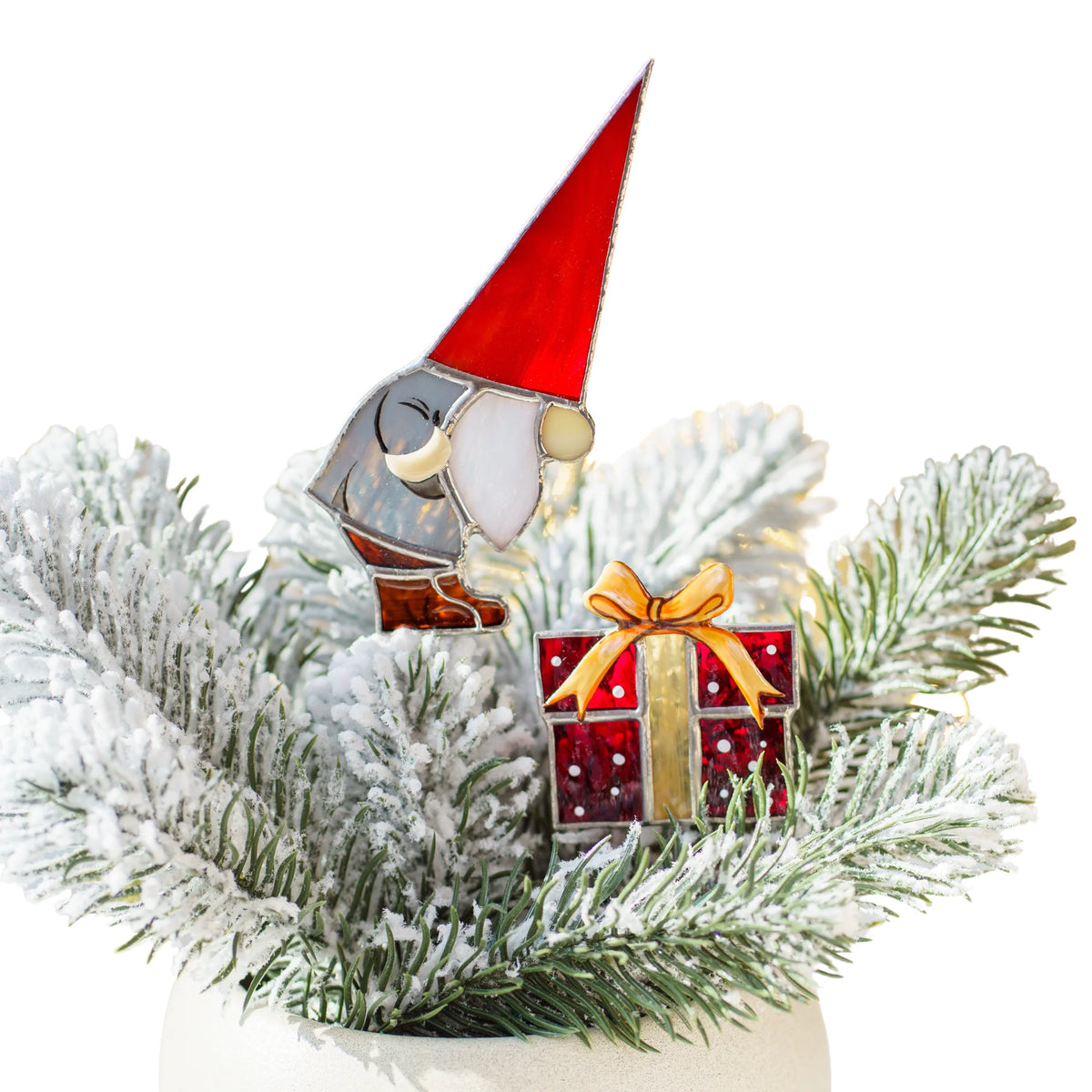 Christmas gnome with gift stained glass plant stakes in frosted fir branches - a gnome in a tall red hat beside a red present with a gold bow, handmade Christmas plant decor