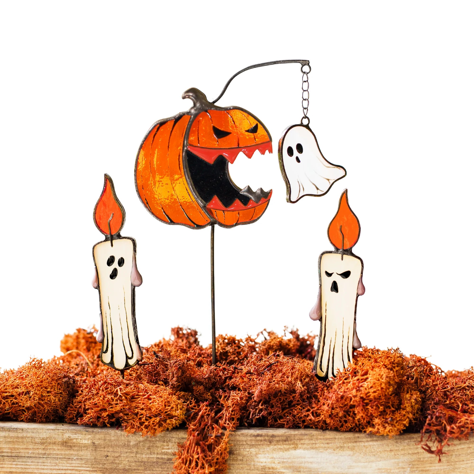 A spooktacular stained glass Halloween set featuring an angry carved pumpkin with a dangling ghost and two spooky candles, perfect as a unique and impressive gift.