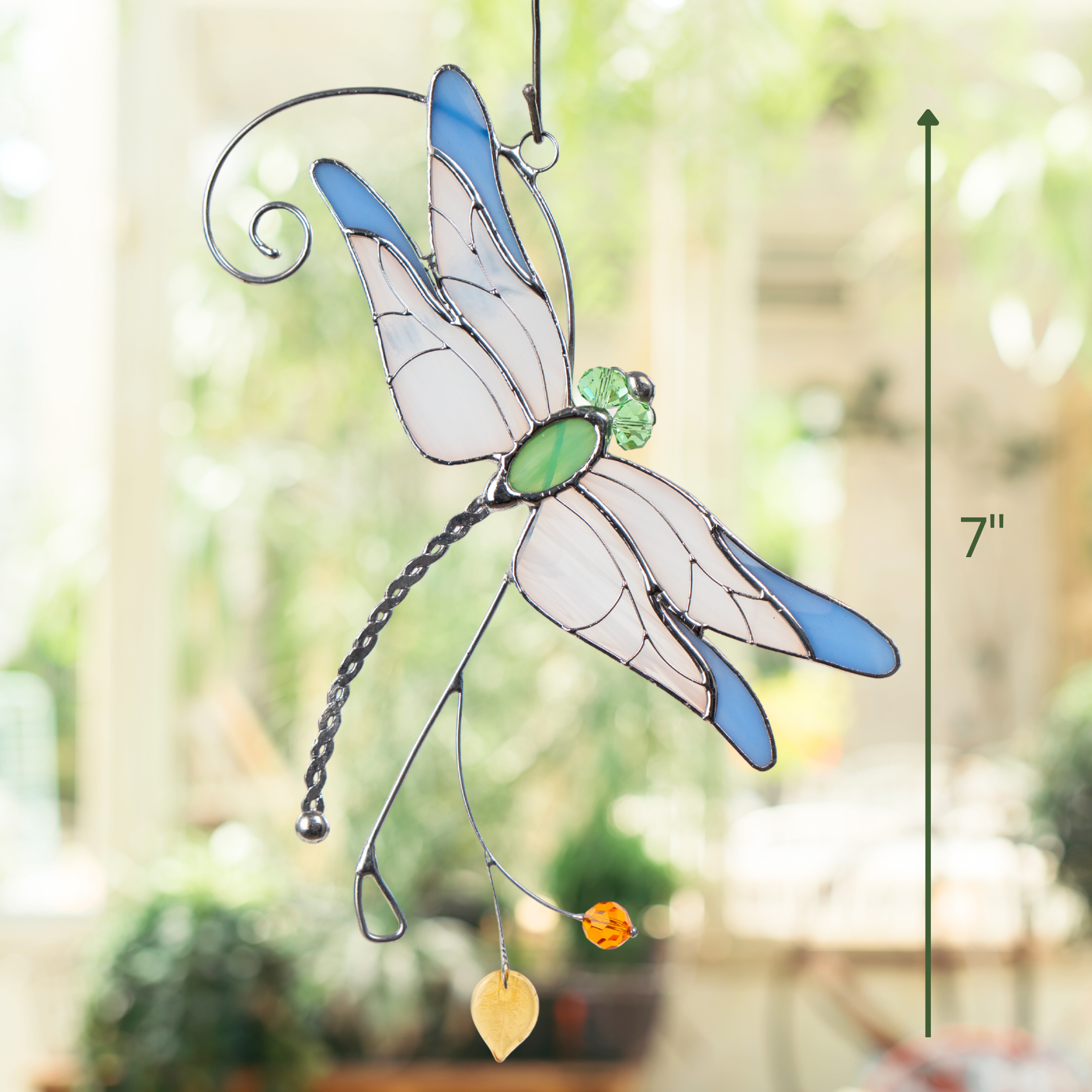 Stained glass dragonfly suncatcher hanging indoors with size indicator showing 7 inches tall.