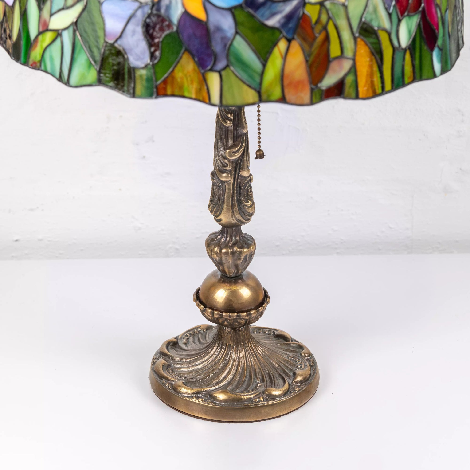 Close-up of decorative metallic base with curved details below stained glass