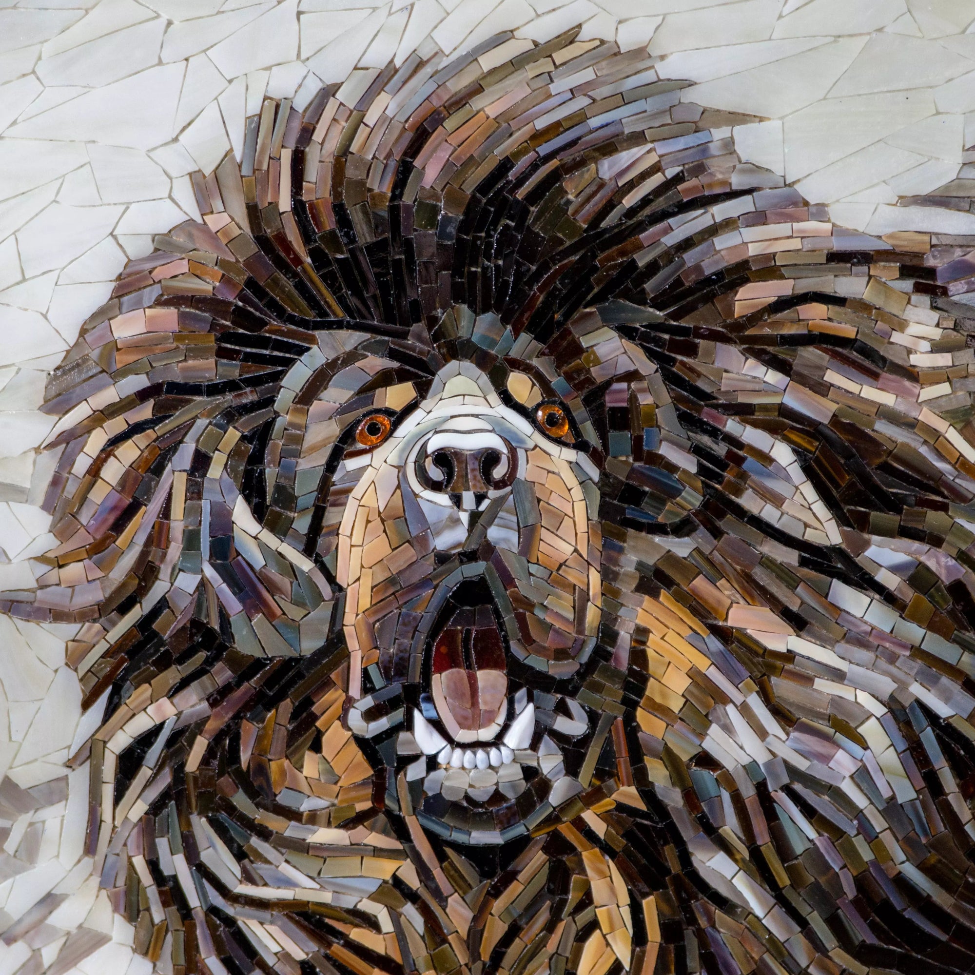 Close-up photo of a stained glass mosaic panel showing a mastiff dog with expressive eyes and defined contours.