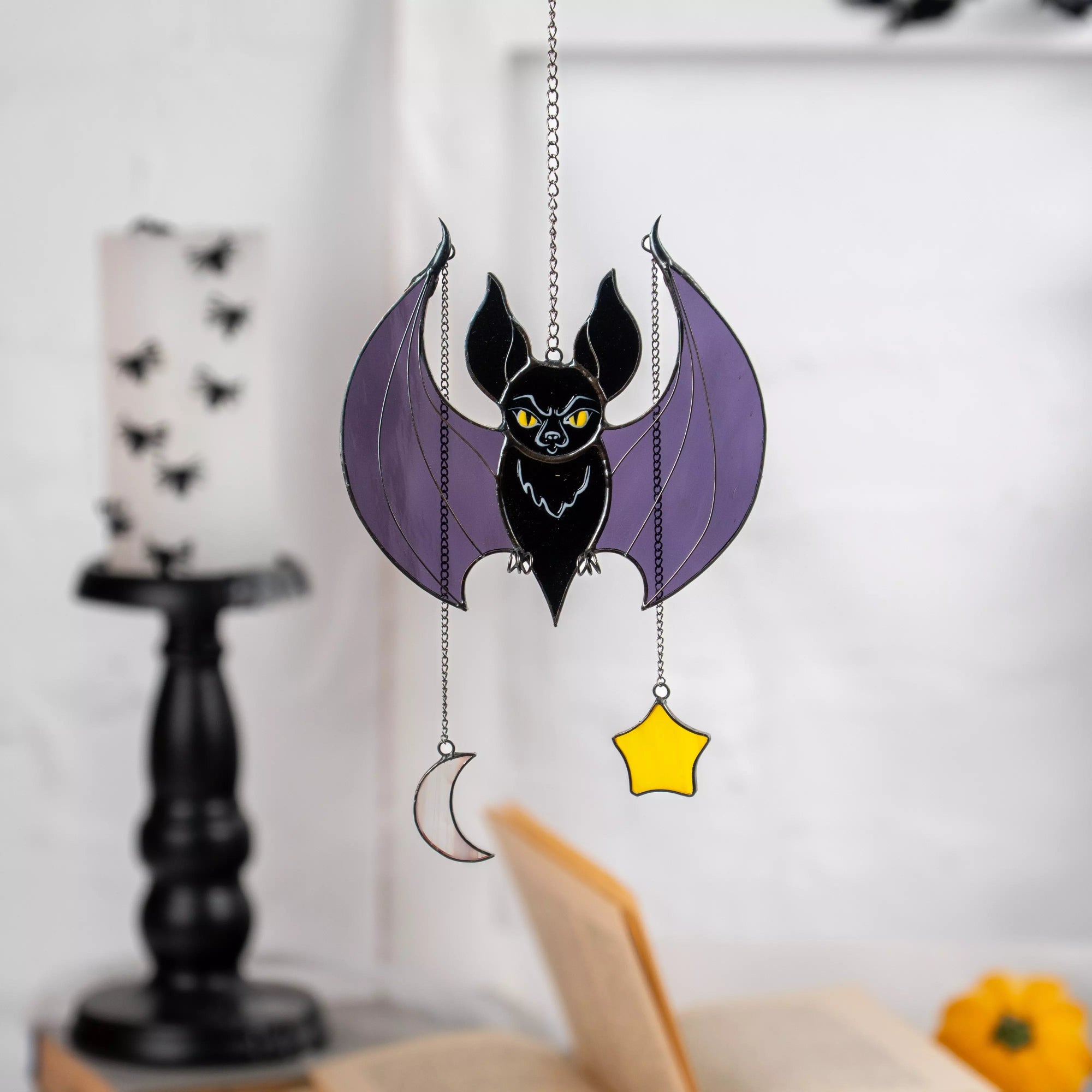 Bat with purple wings, yellow eyes, moon and star charms hanging in spooky room