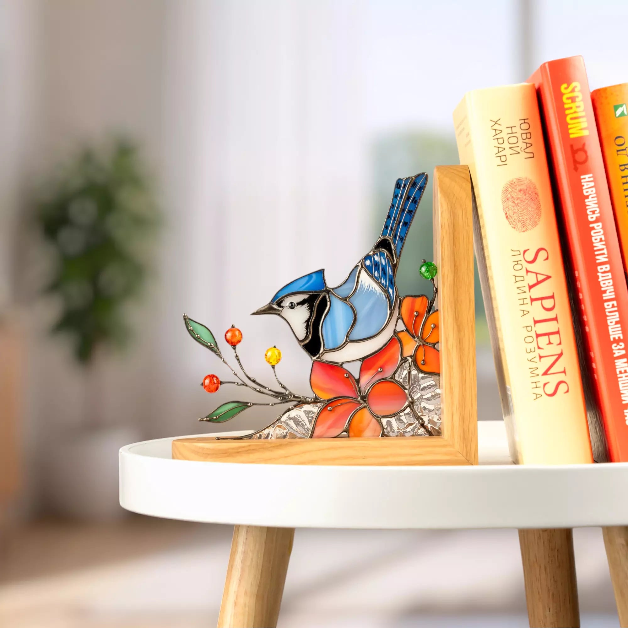 Blue jay stained glass bookend styled in a bright interior with books.