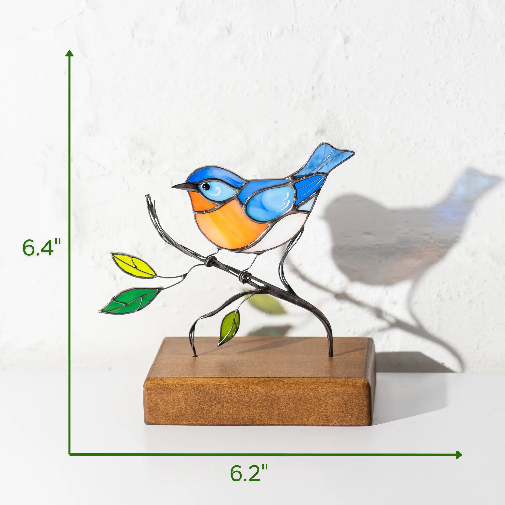 Stained glass bluebird suncatcher with dimensions: 6.4 inches tall, 6.2 inches wide. Mounted on stained wood base.