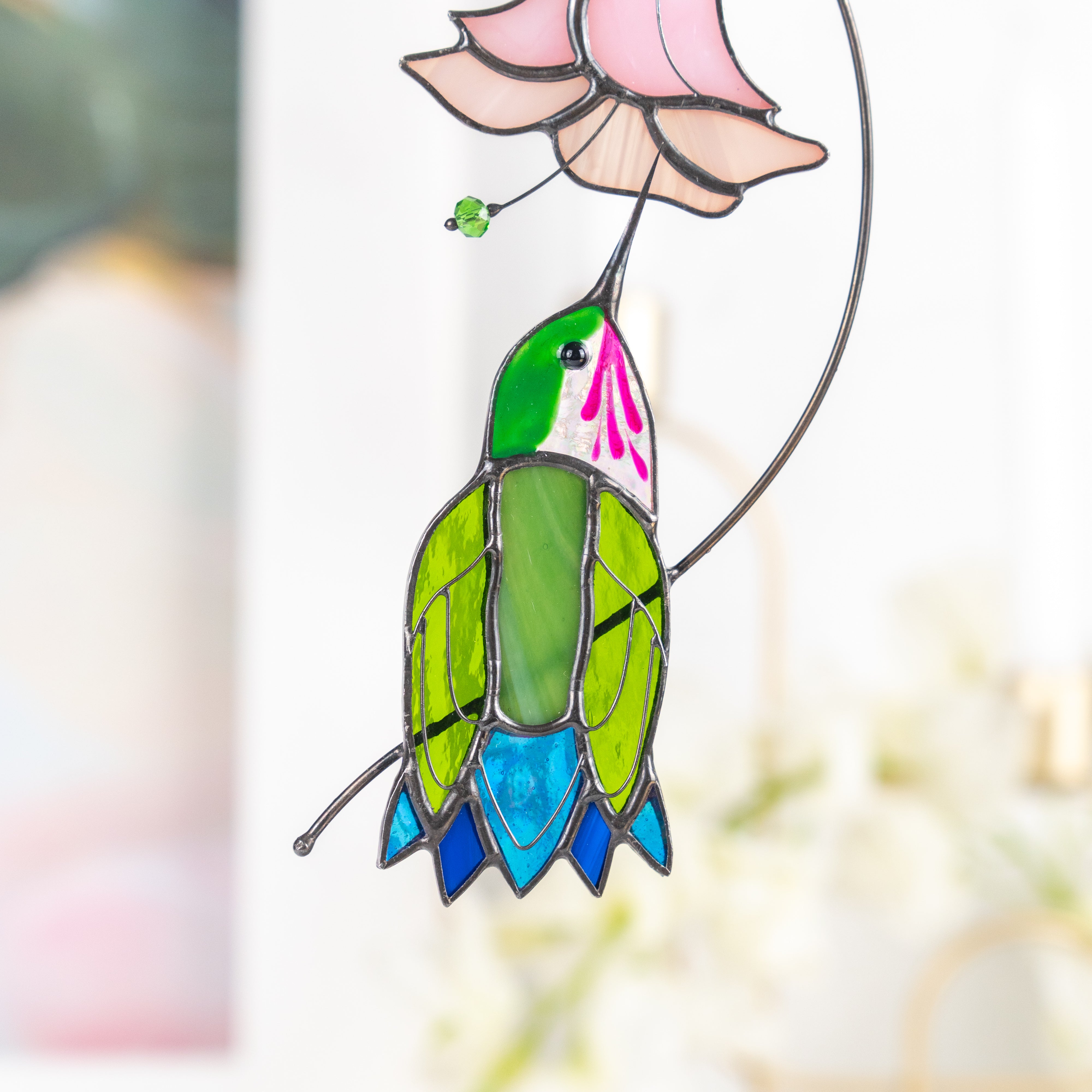 Close-up of the lower half of the stained glass hummingbird, showing detailed glass texture and vibrant colors.