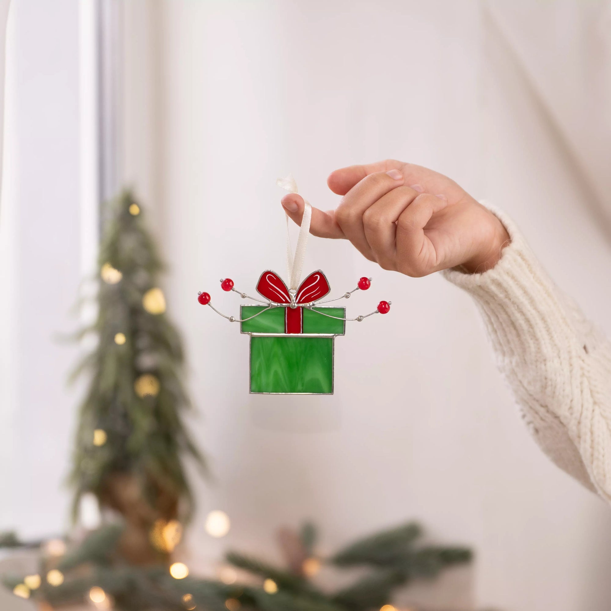 Stained glass green gift box with a red bow and red beads, hand-crafted for the holidays.