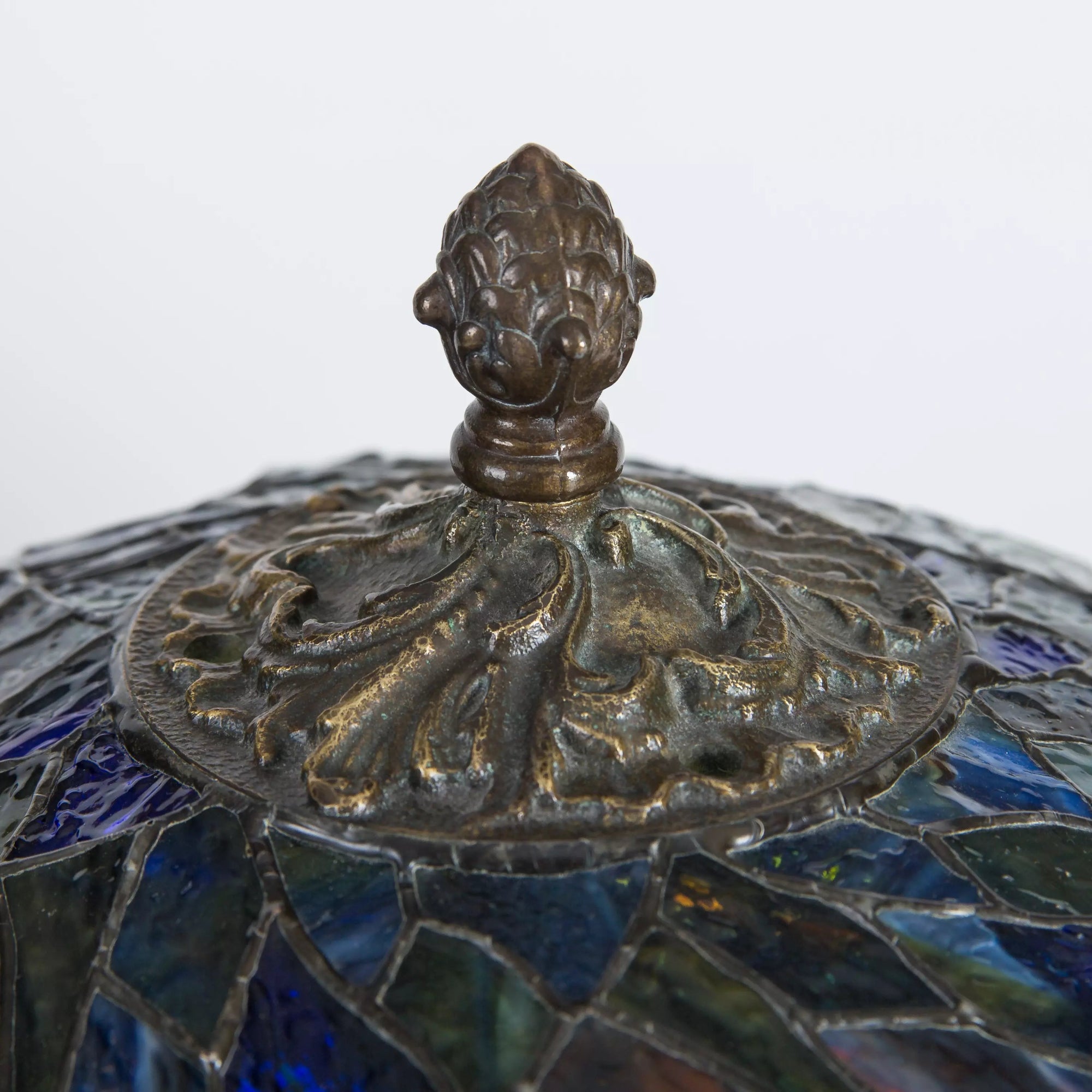 Finial detail on top of the lamp's dome with leaf-like cast bronze patterning