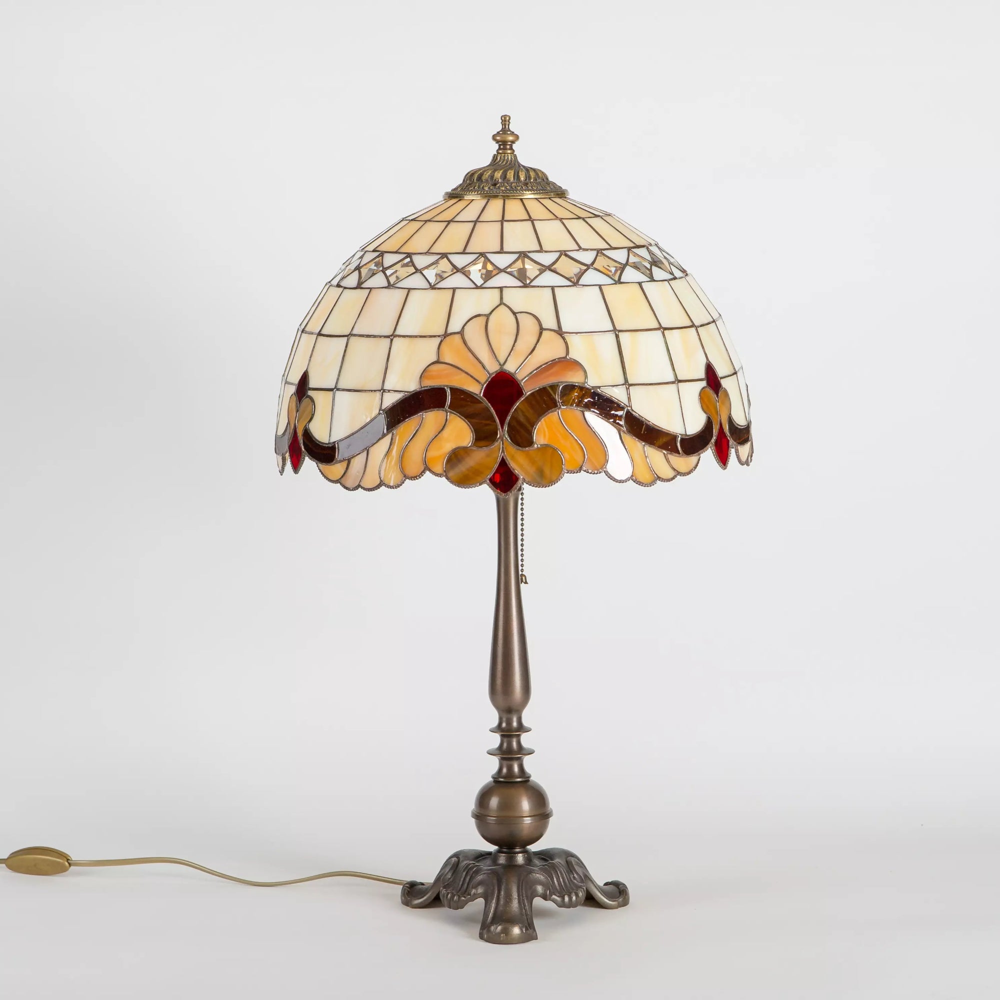 Side view of stained glass lamp on bronze-tone base with cord and pull chain