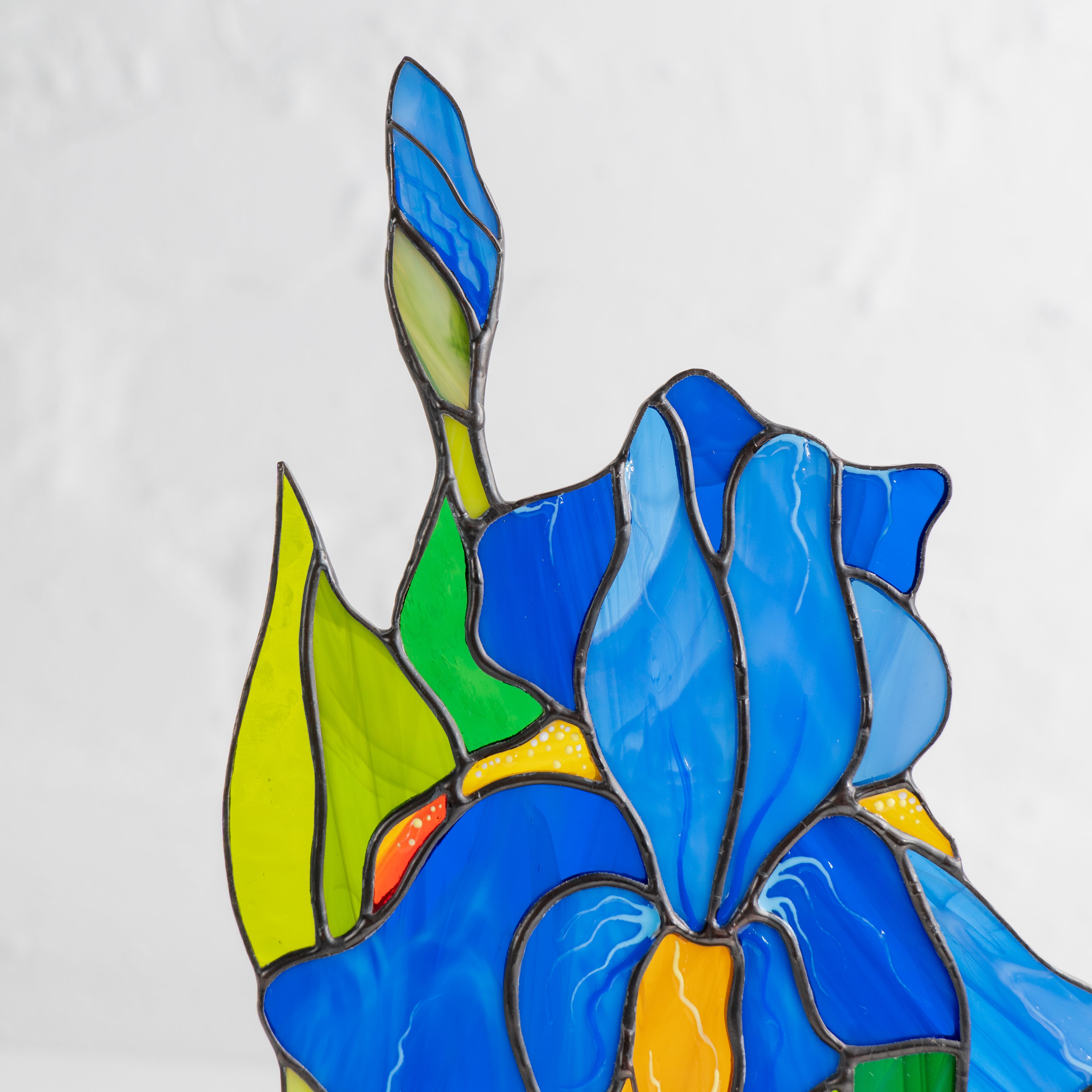 Close-up view of upper part of stained glass iris showing intricate petal and leaf detail.