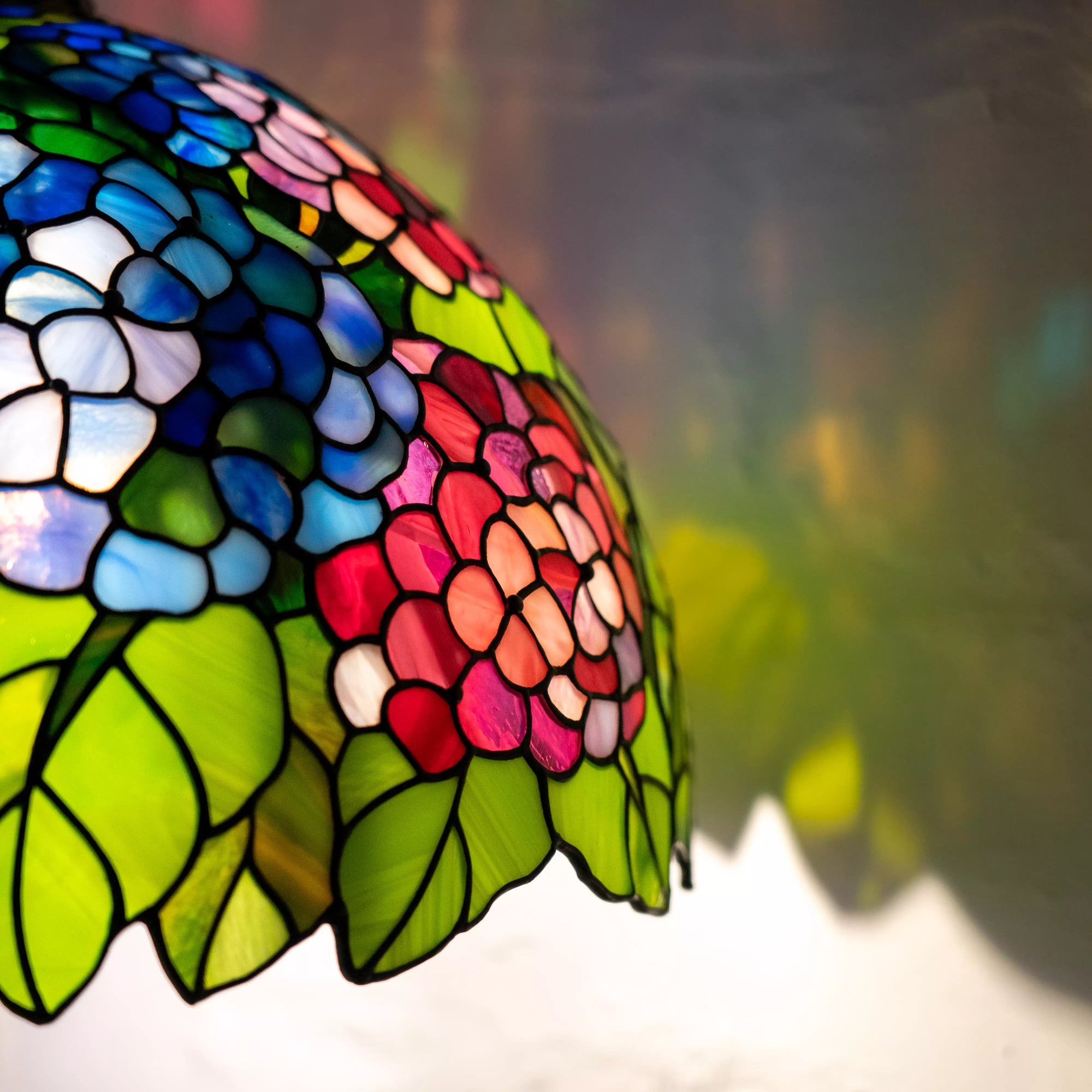 Colorful hydrangea stained glass lampshade glowing and projecting floral shadows.