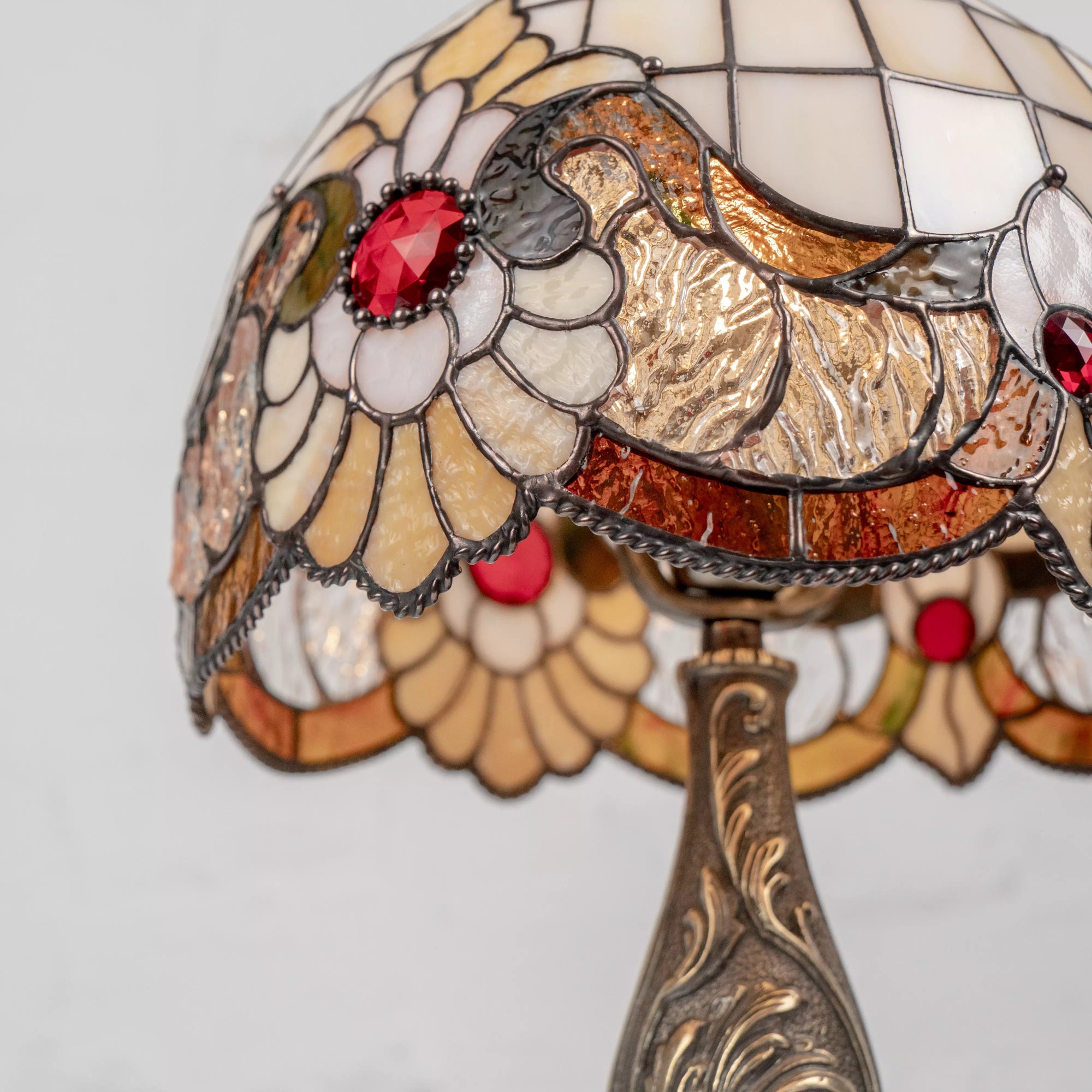 Close-up of stained glass detail with bold red crystal center and curved cream-colored glass petals