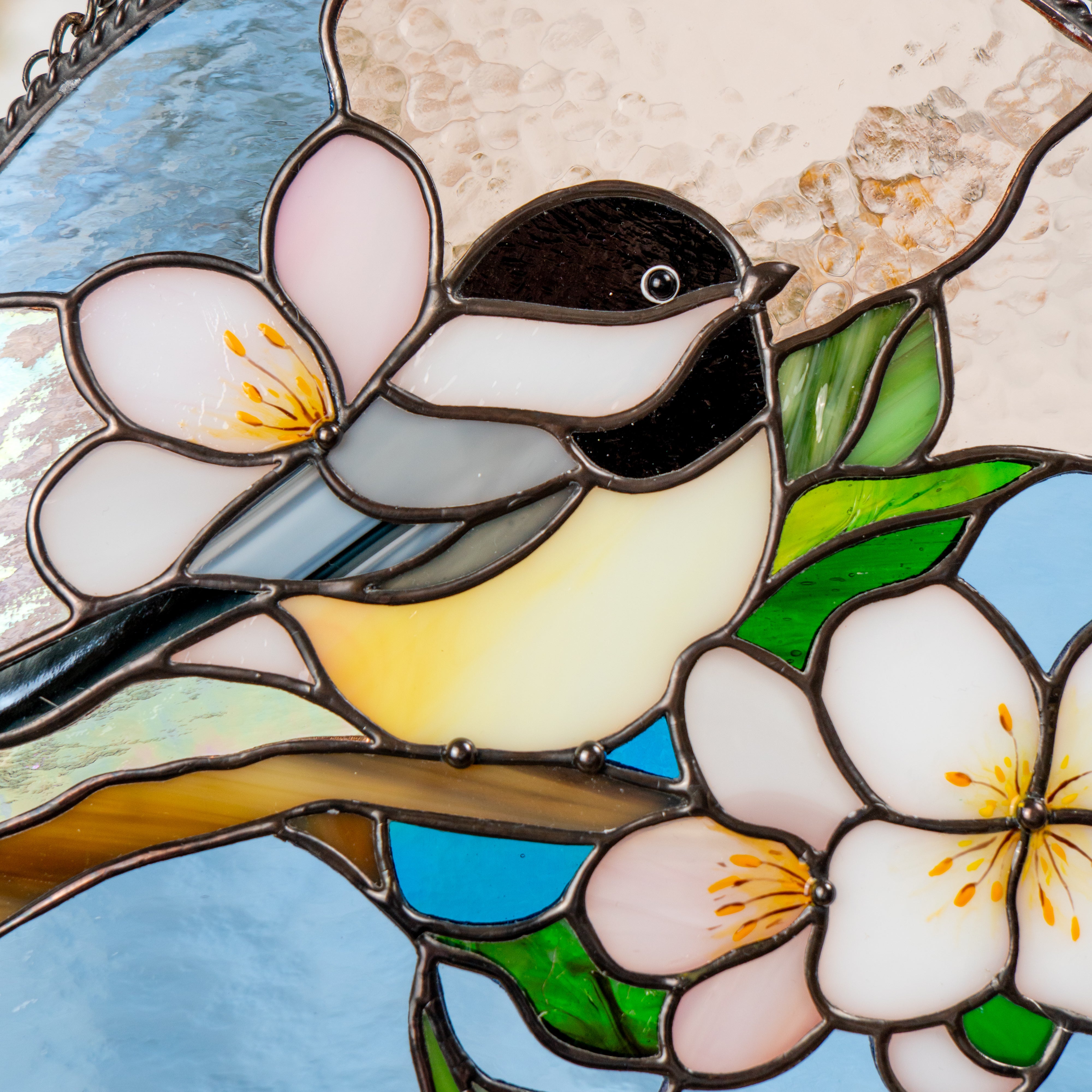 Detailed view of the chickadee's head and surrounding pink flower, highlighting the craftsmanship of the stained glass panel