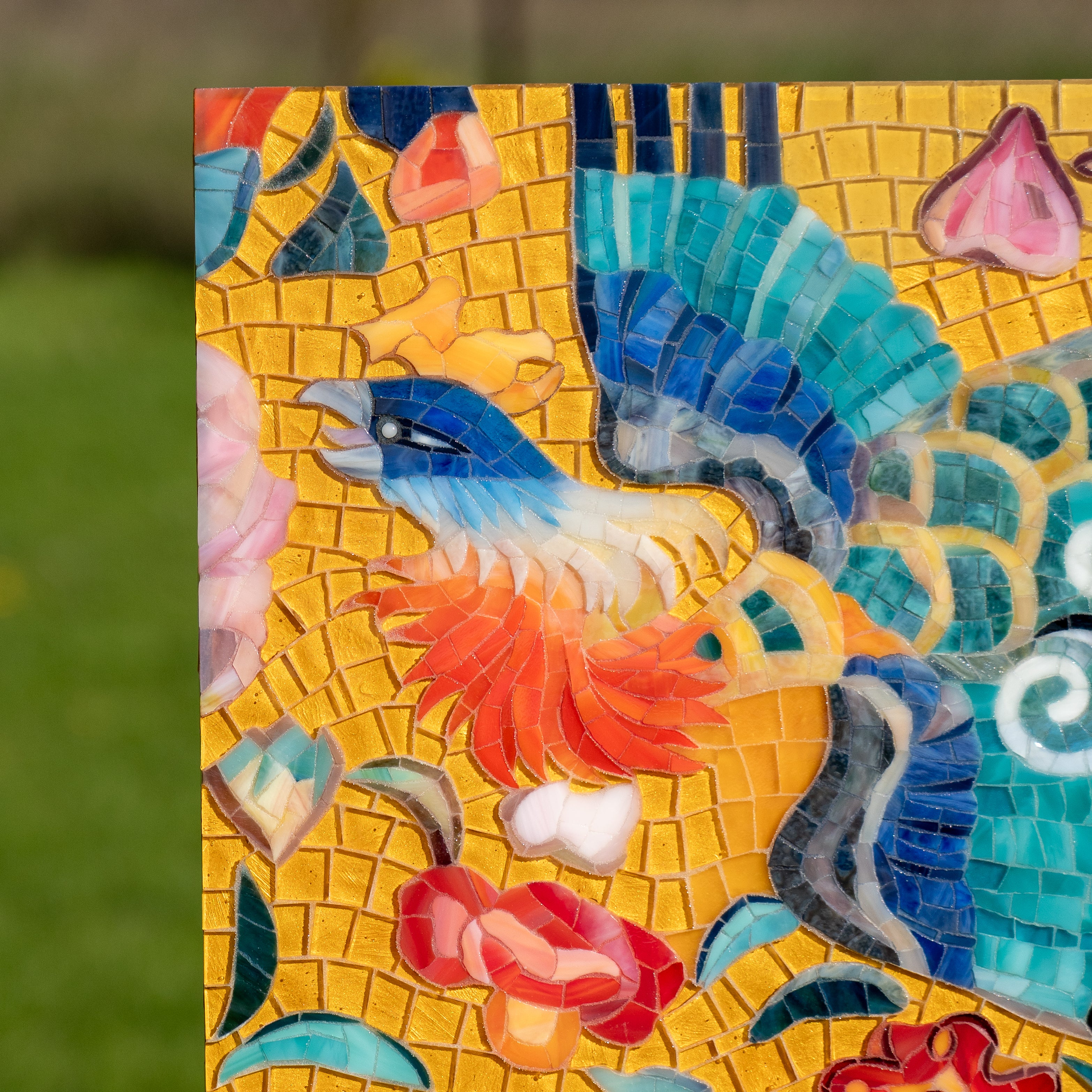 Detailed section of the mosaic showing a blue and orange bird among colorful flowers on a warm yellow background.