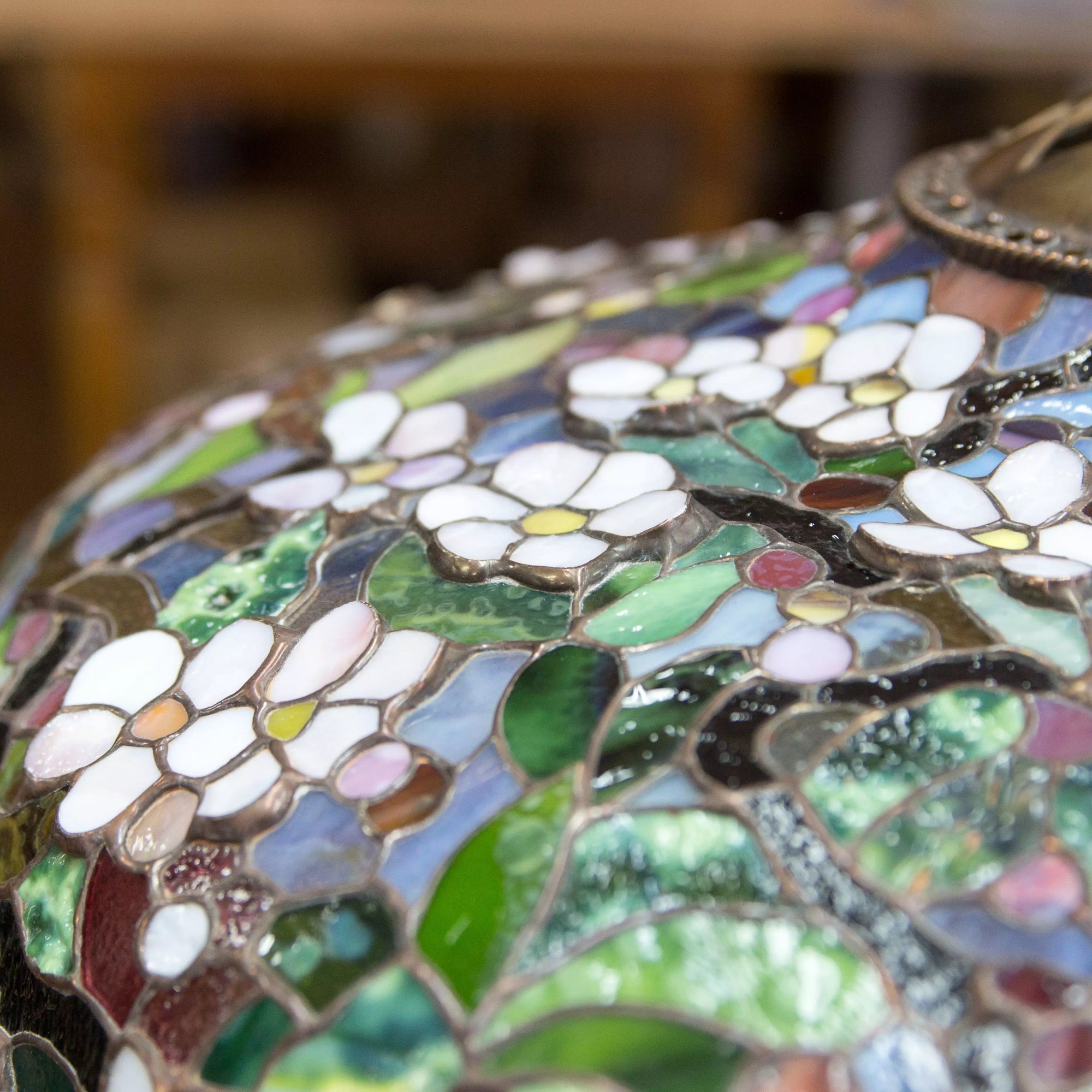 Macro shot of stained glass surface highlighting petal and leaf textures in a floral mosaic.