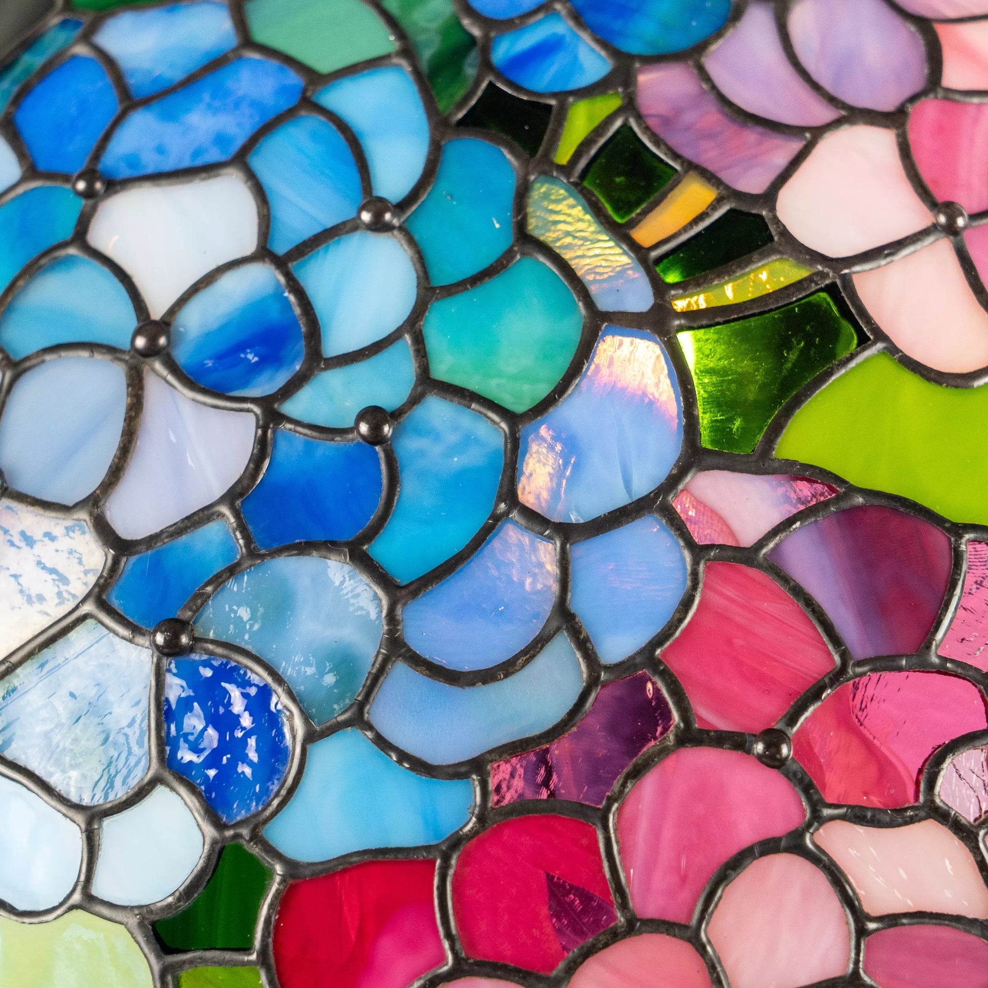 Vivid stained glass mosaic in blue and pink flower petals with rich texture and shine.