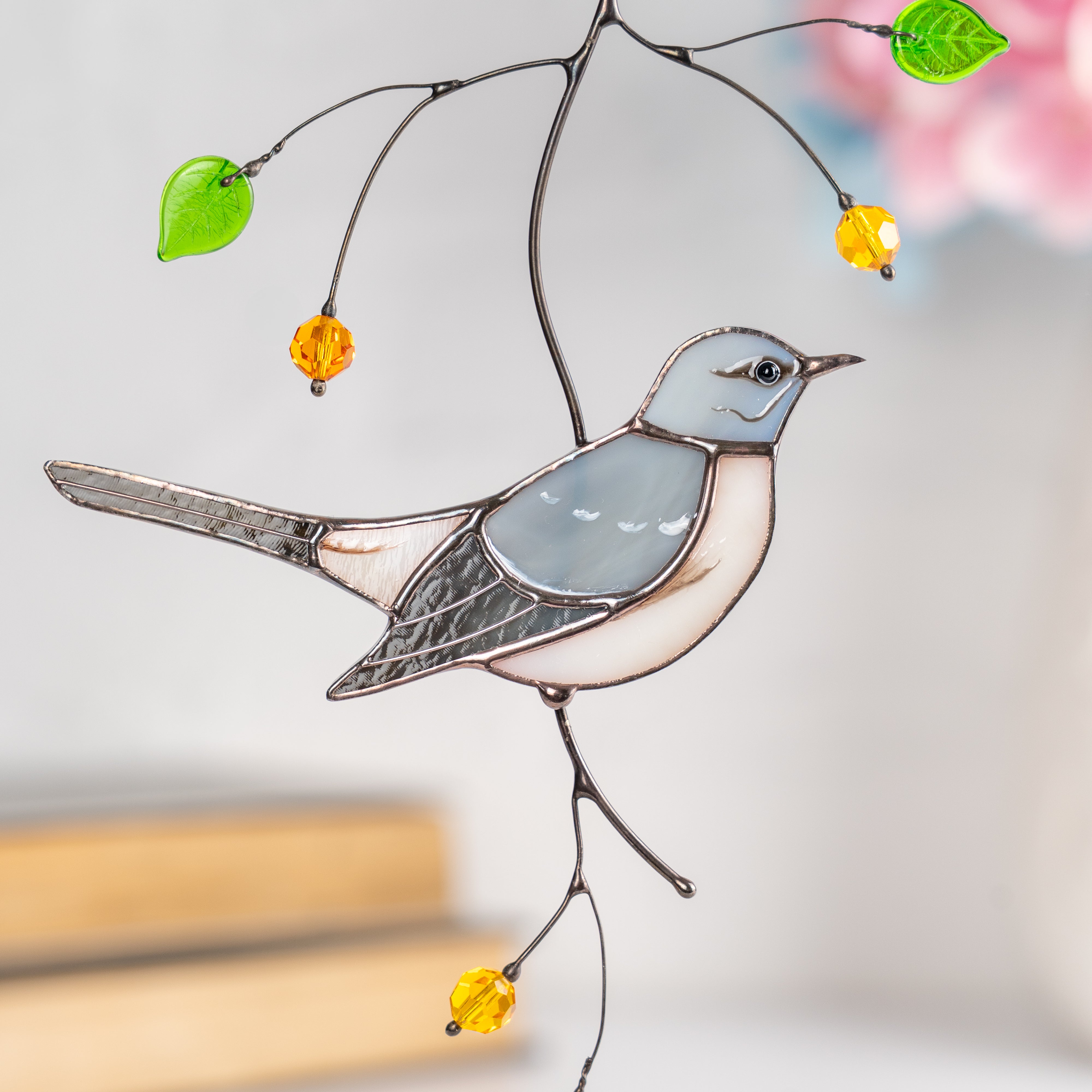 Stained glass light grey mockingbird with detailed wing and amber beads, displayed indoors.