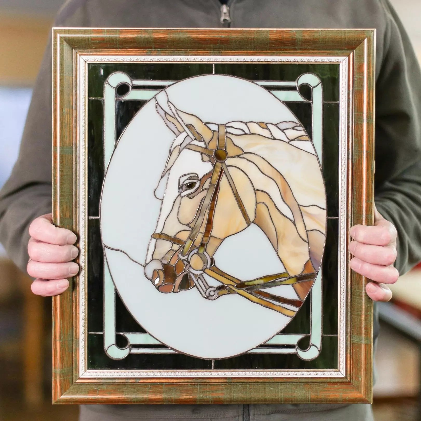 Frontal view of a framed stained glass panel with detailed beige horse head and decorative green frame.