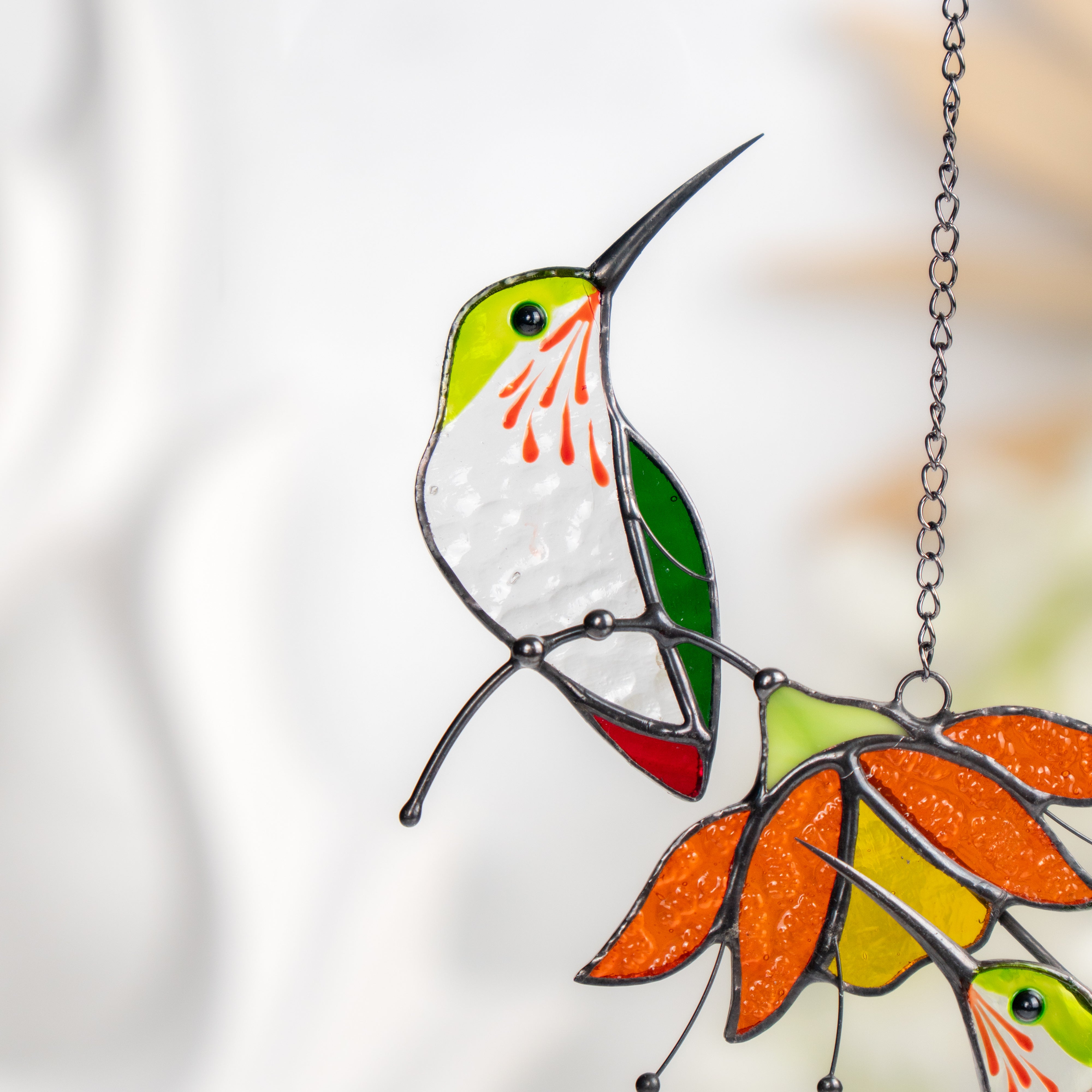 Detailed view of upper stained glass hummingbird with green wing and textured white glass body.