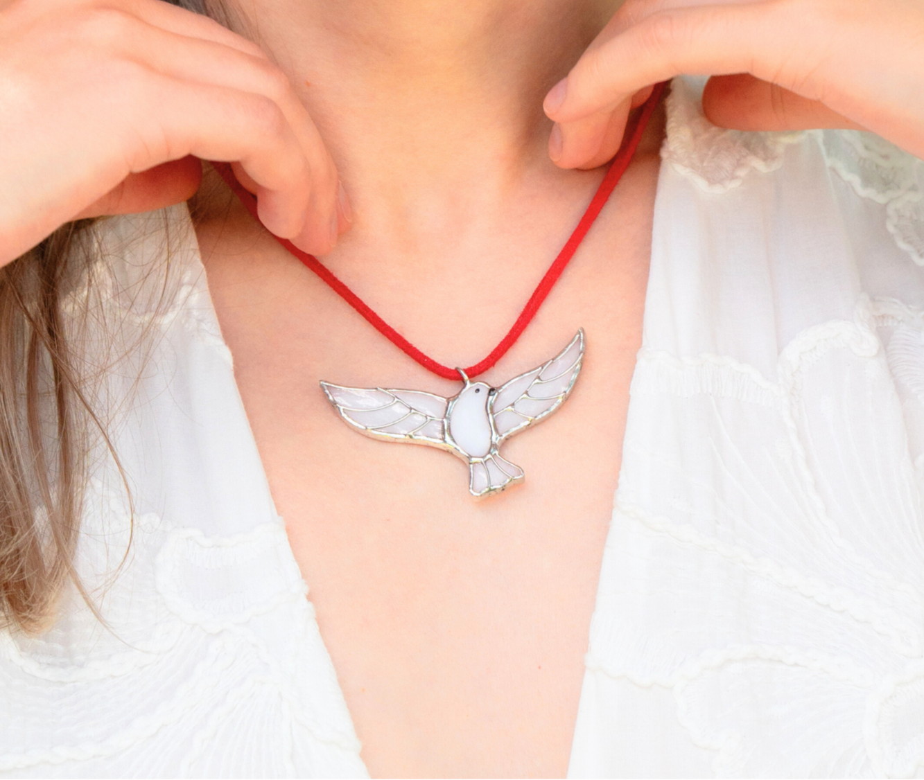 A close-up of a person wearing a bird-shaped necklace