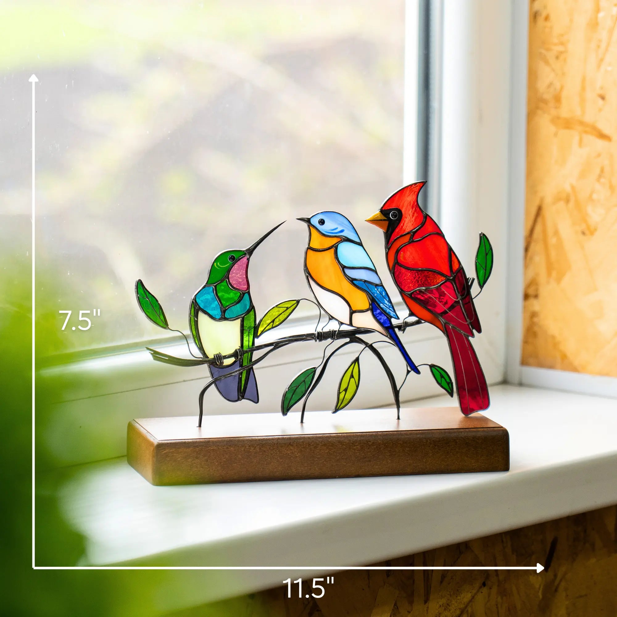 Hummingbird, bluebird, and cardinal stained glass suncatcher shown on window ledge with size 11.5 x 7.5"