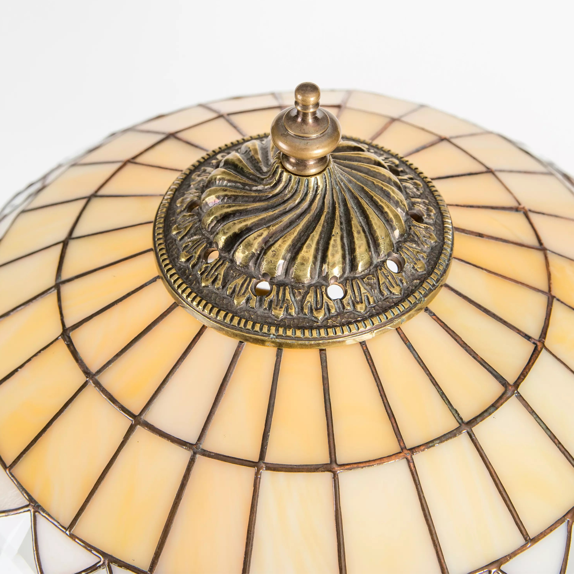 Vintage-style brass finial detail on top of cream and amber stained glass dome