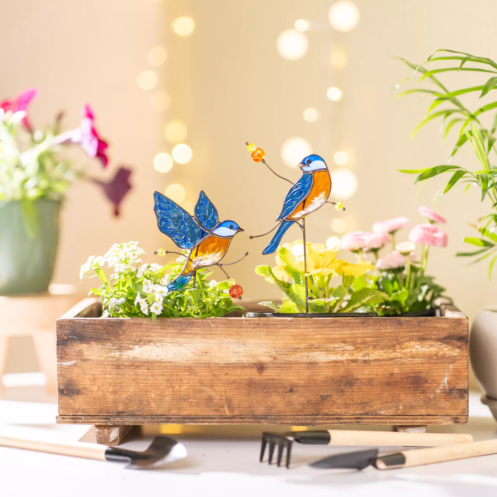 Decorative garden plant scene with wooden planter, bluebirds, and flowers on a blurred background