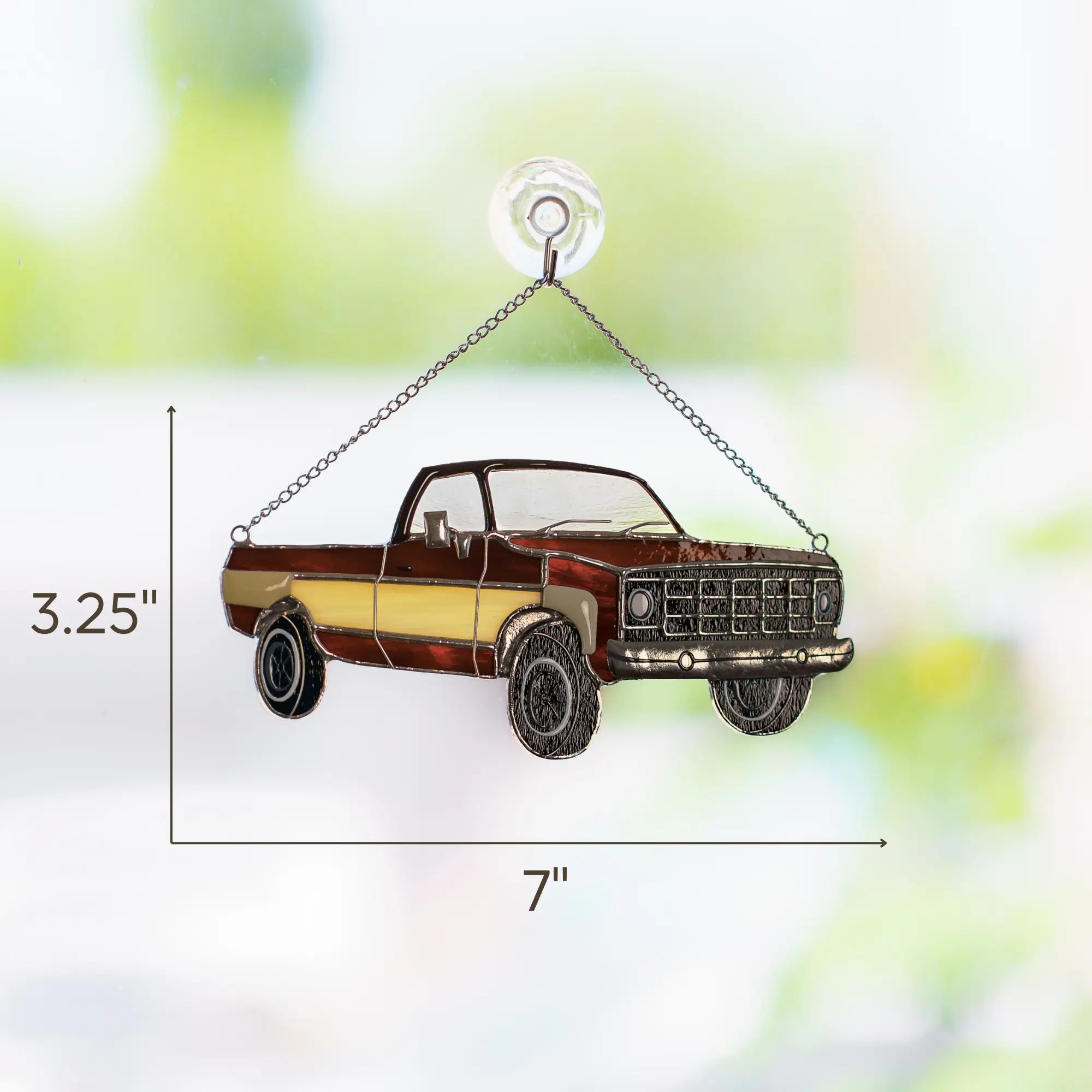Stained glass metal truck ornament with dimensions: 3.25 x 7 inxhes on a blurred natural background