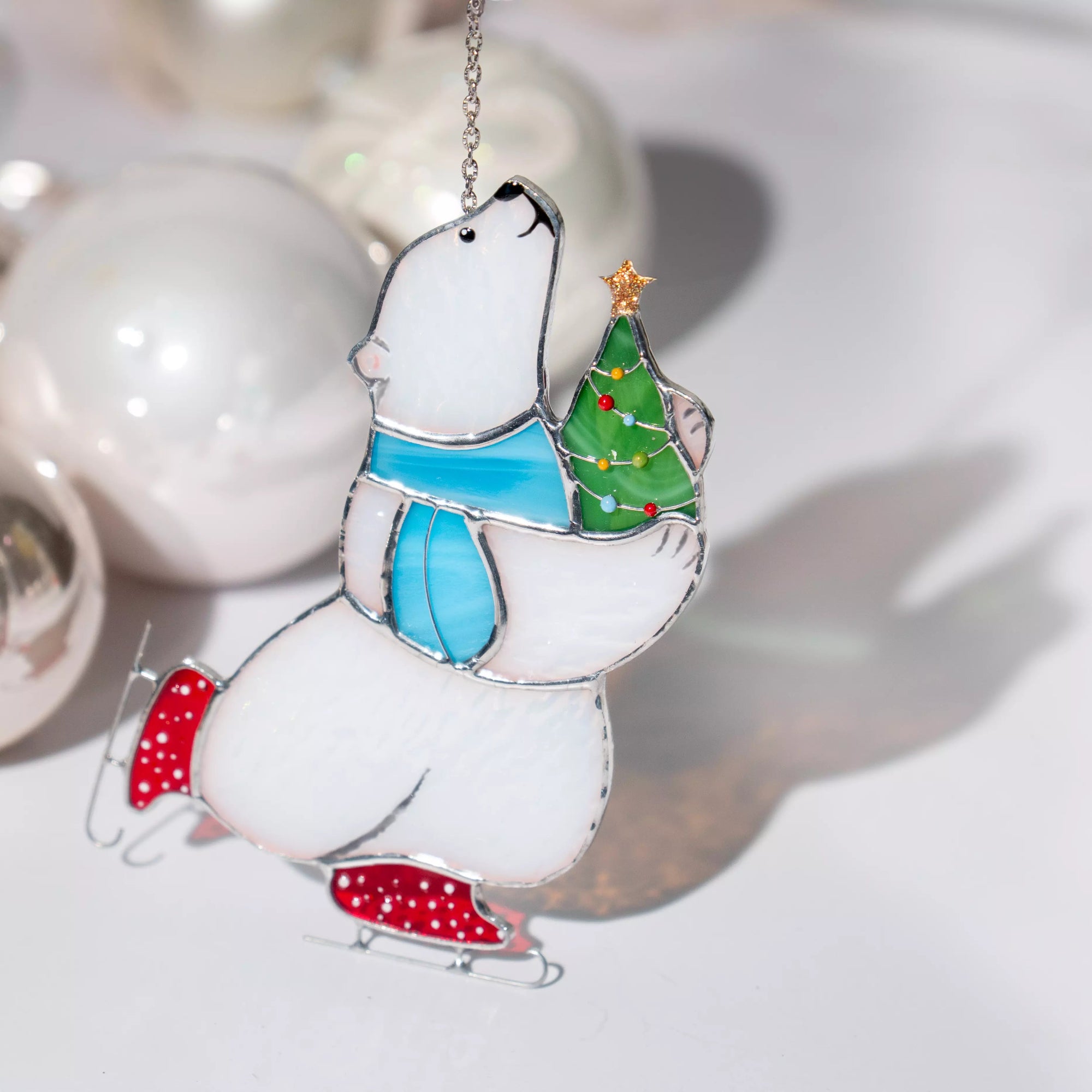 Stained glass polar bear ornament with a Christmas tree and Christmas decor in the back