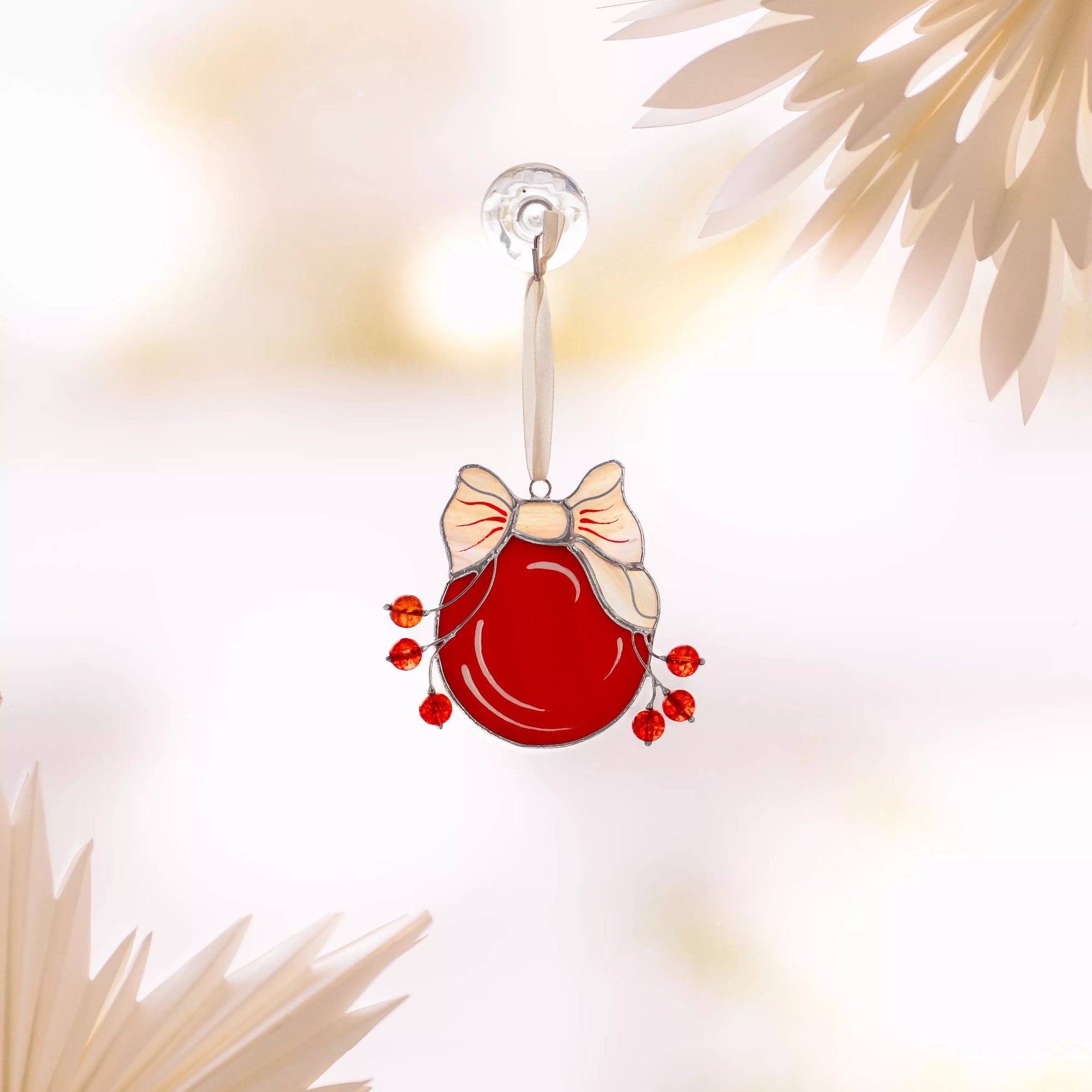Decorative red stained glass ornament with a bow on a blurred background