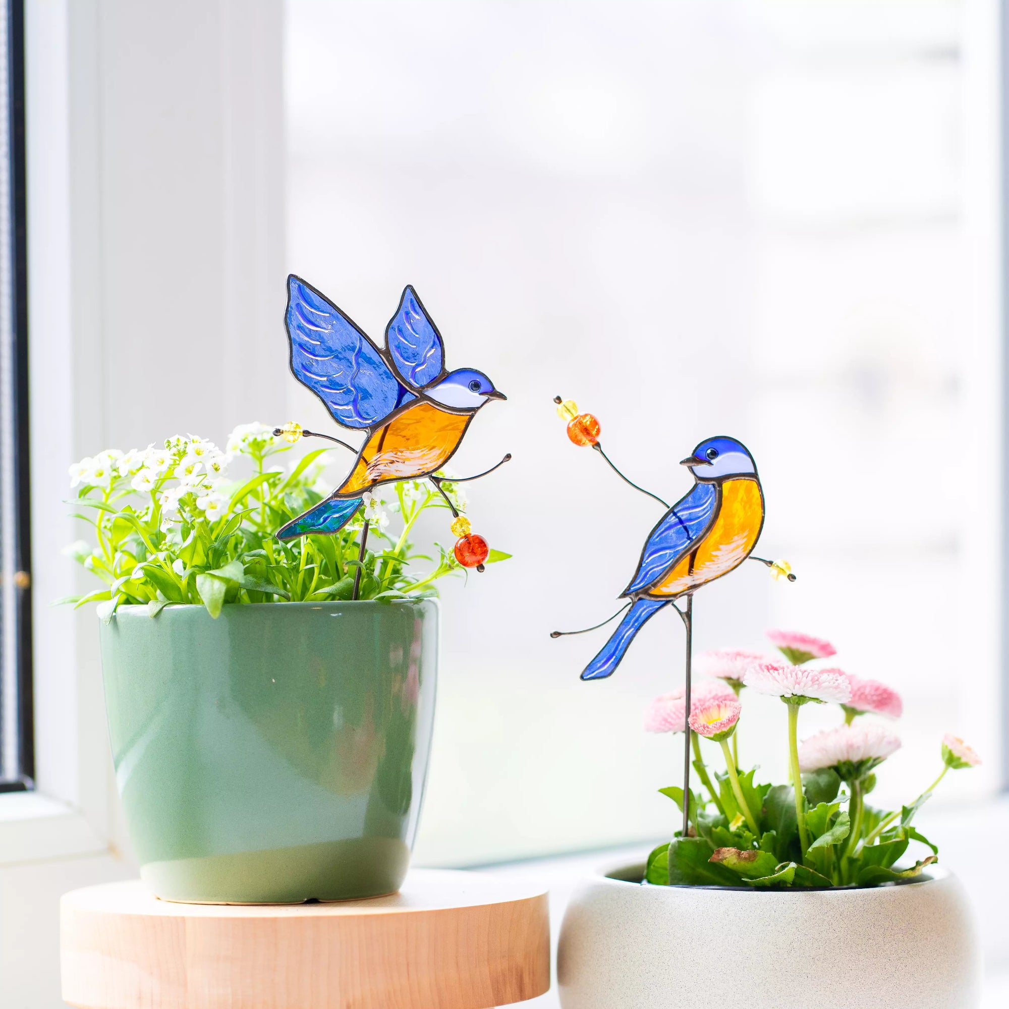 Decorative stained glass bluebirds on plants with a light background