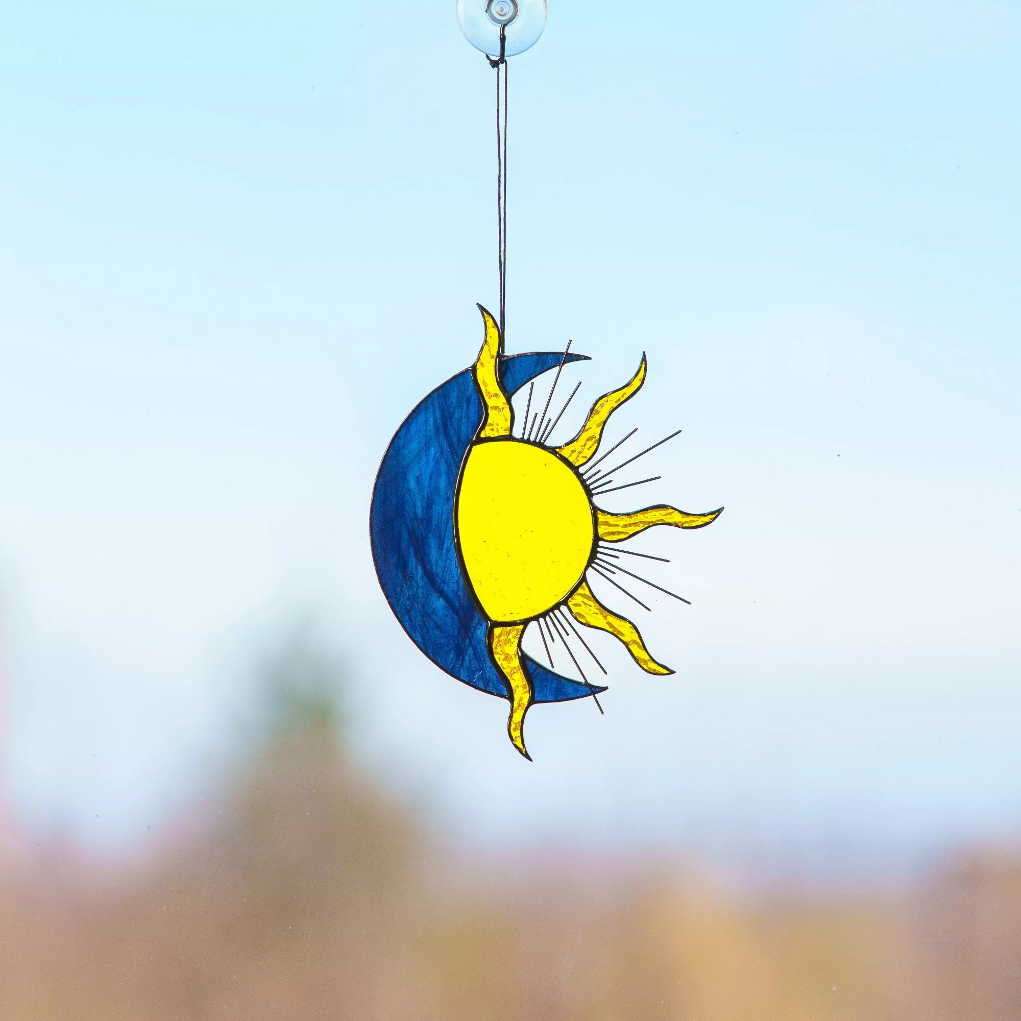 Decorative sun and moonstained glass window hanging ornament against a blurred natural background
