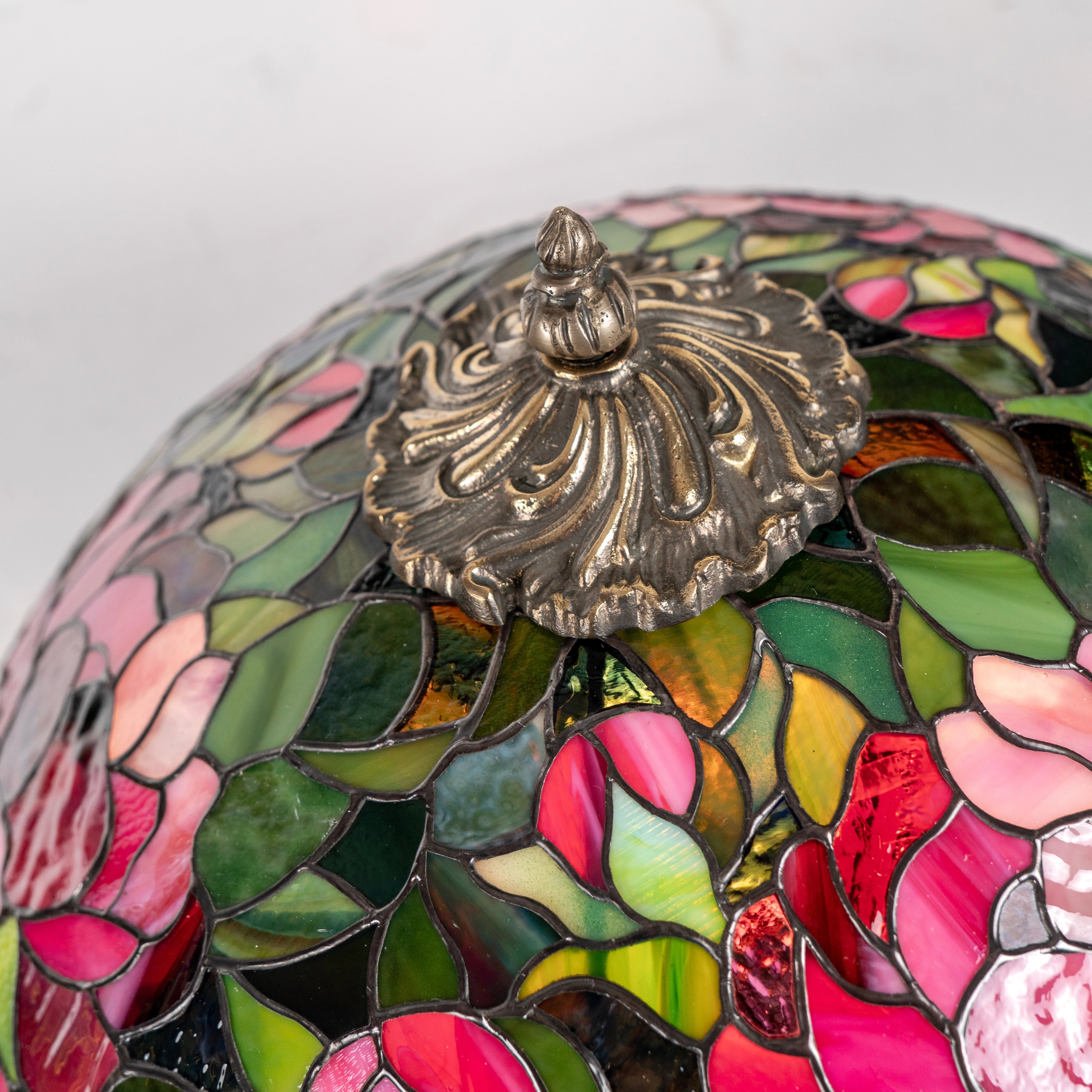 Decorative lamp with stained glass design and ornate metal fixture on a white background