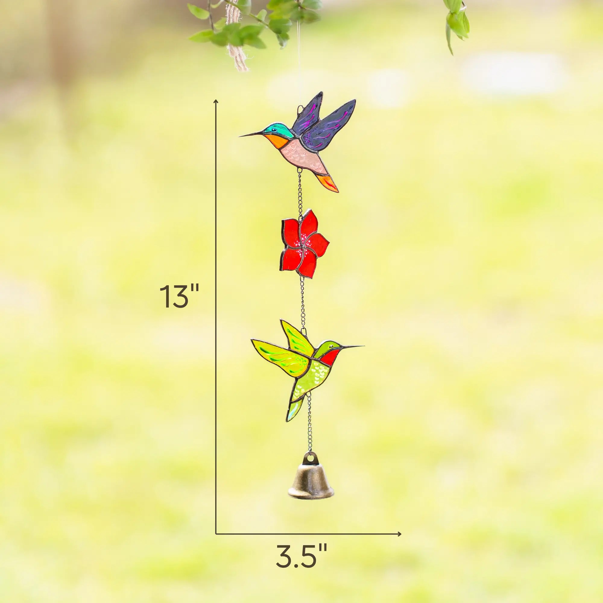 Stained glass wind chime with hummingbirds and a flower on a blurred green backgroundwith dimensions 3.5 x 13 inches