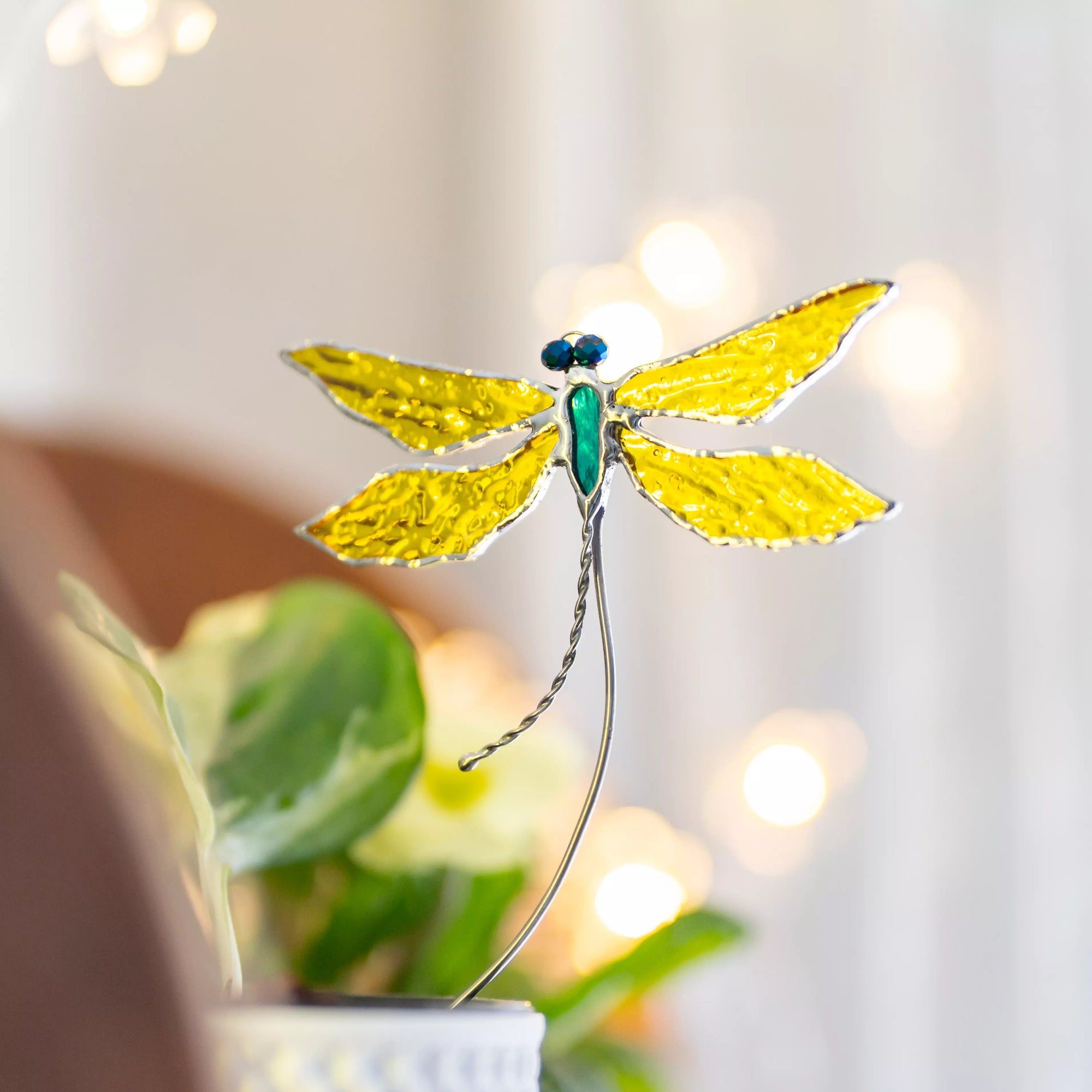 Stained glass yellow dragonfly plant stake with blurred background