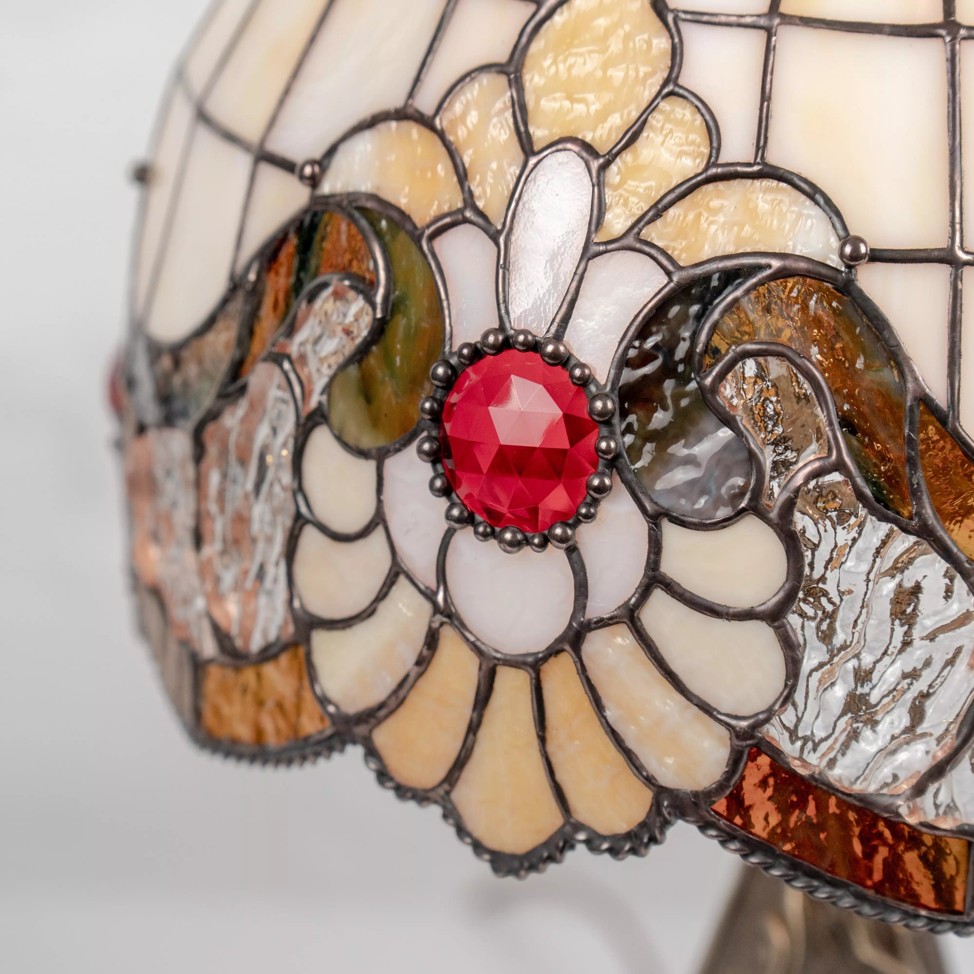 Close-up of stained glass bold red crystal center and curved cream-colored glass petals