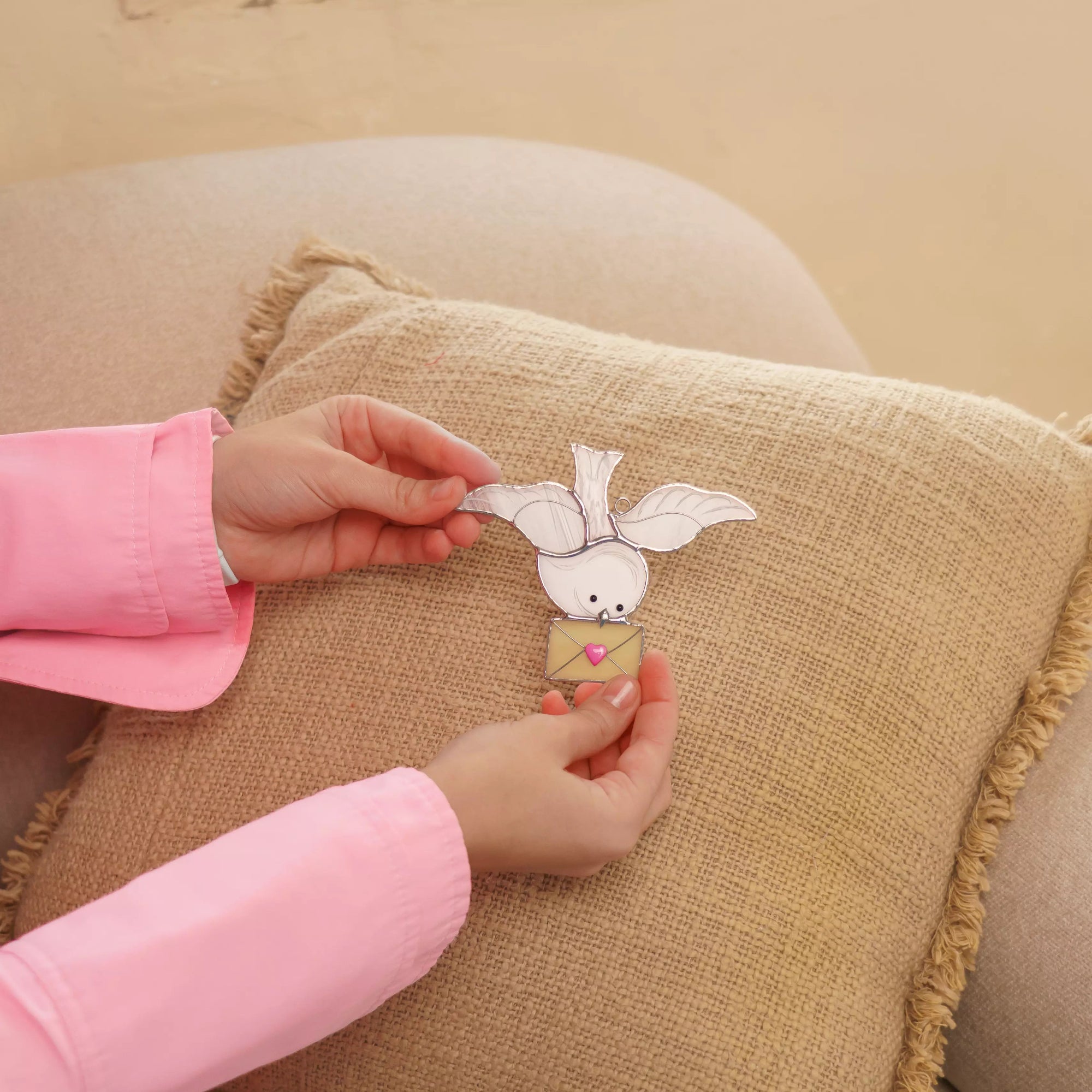 Dove stained glass suncatcher shown in a cozy home setting on a soft pillow.