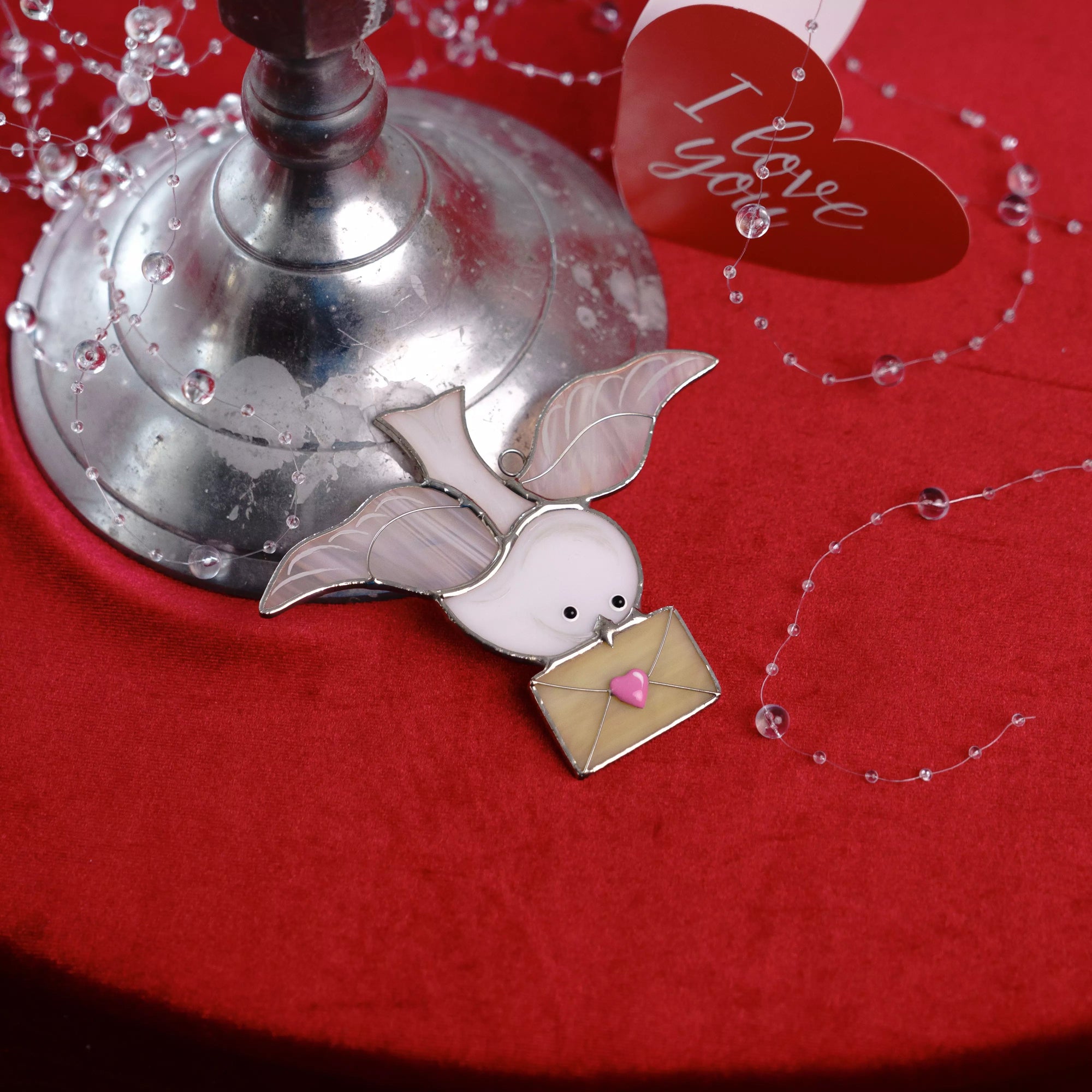 Dove stained glass suncatcher styled on a red background with romantic details.