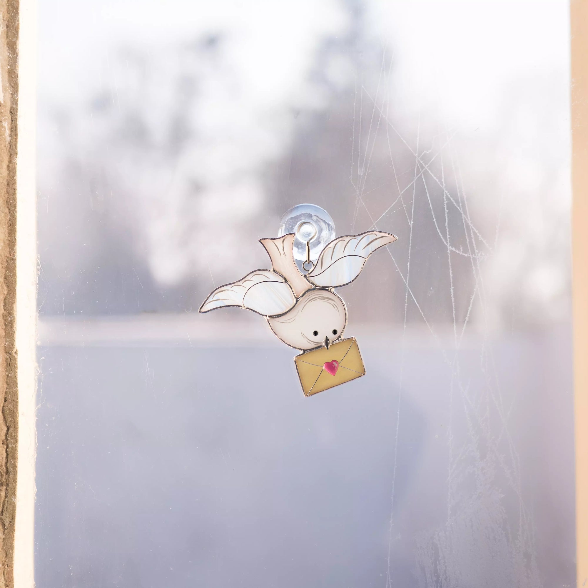 Dove stained glass suncatcher displayed on a window using a suction cup.