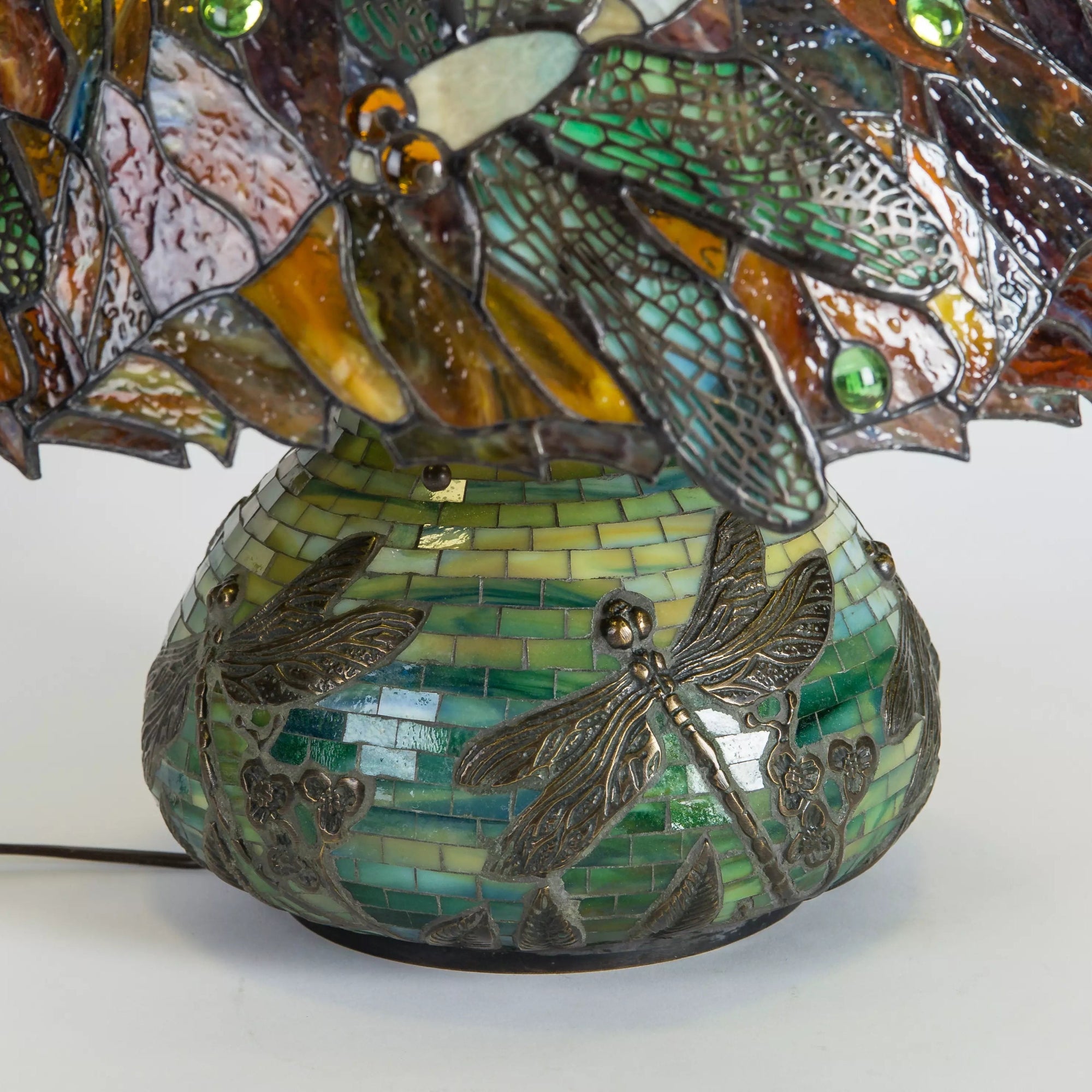 Close-up of green mosaic base with metal dragonfly accents and floral detailing