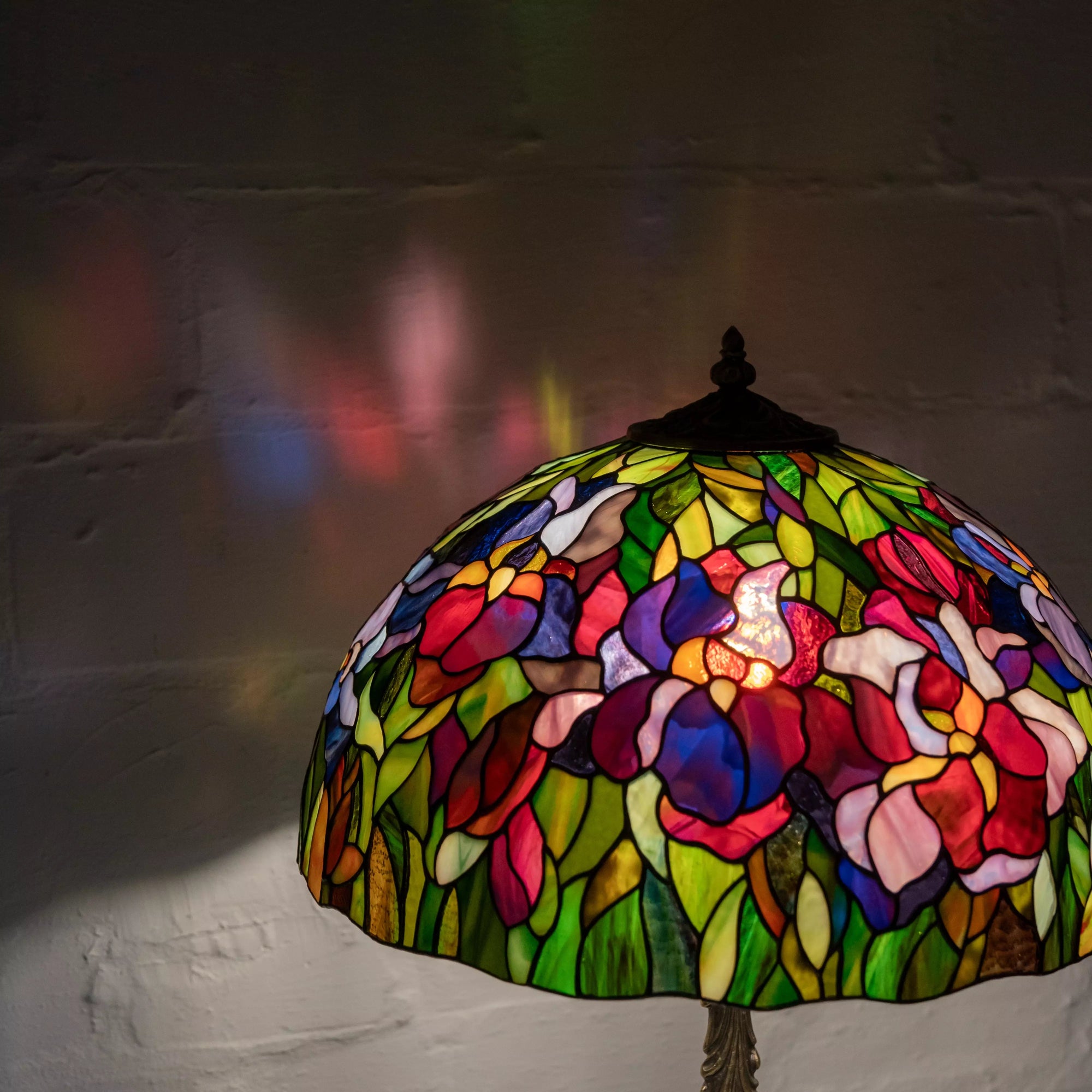 Lamp glowing in the dark with bright iris colors reflecting on the wall