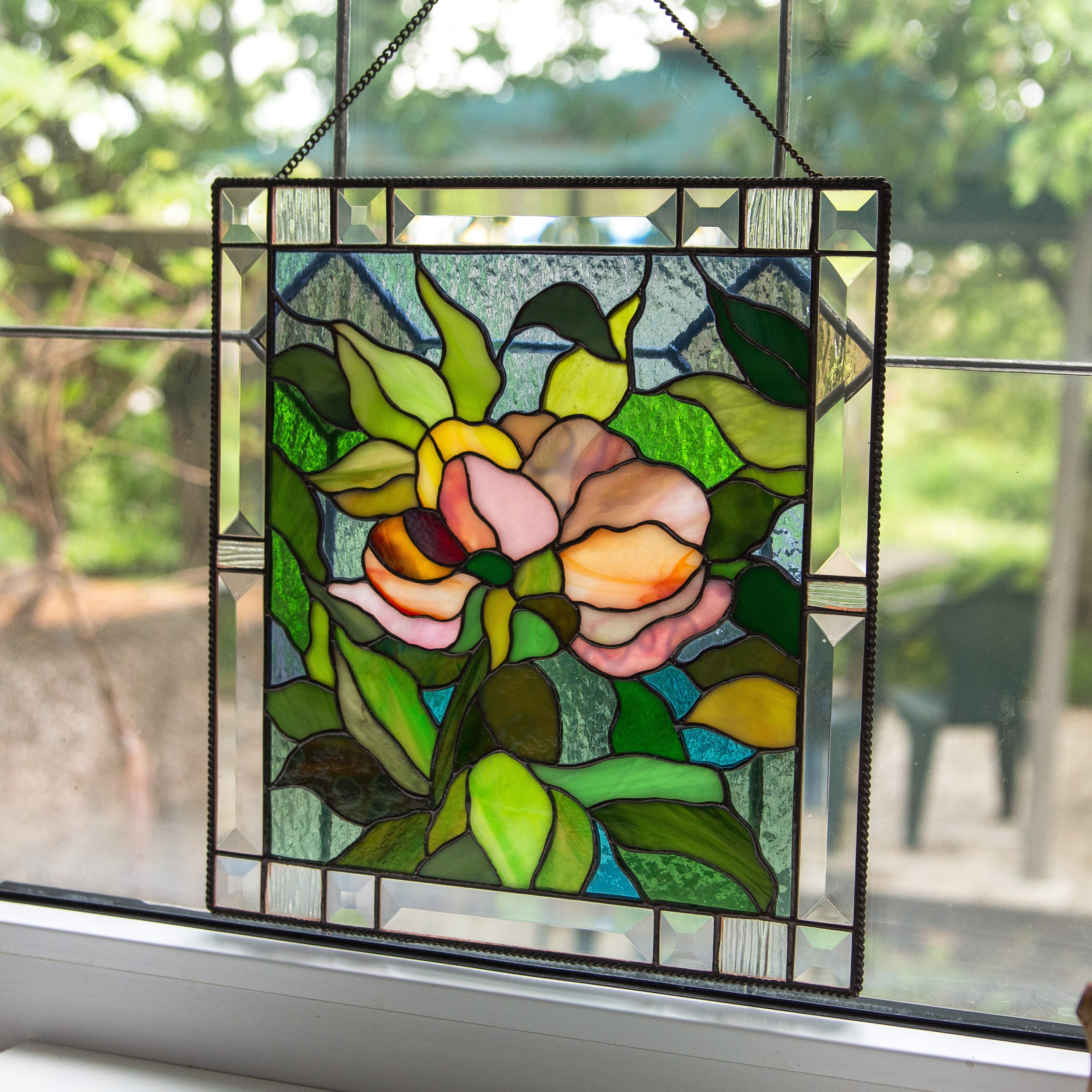 Stained glass panel with floral design hanging on a window