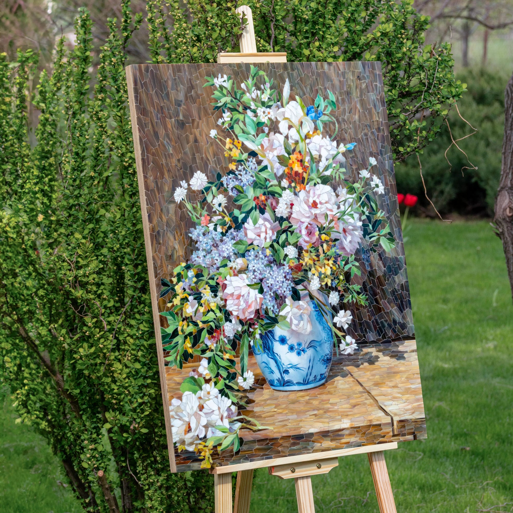 Floral mosaic inspired by Spring Bouquet on an easel outdoors with greenery in the background