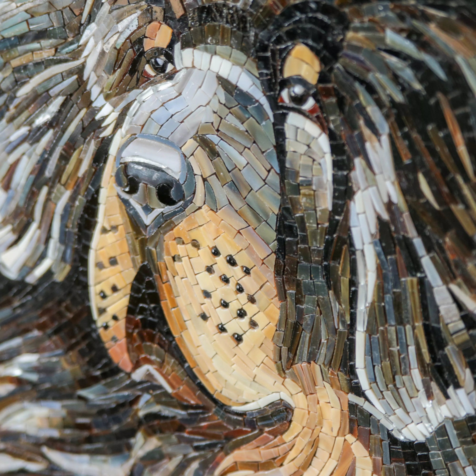 Stained glass piece of a mastiff dog with lifelike expression and warm-toned mosaic sections.