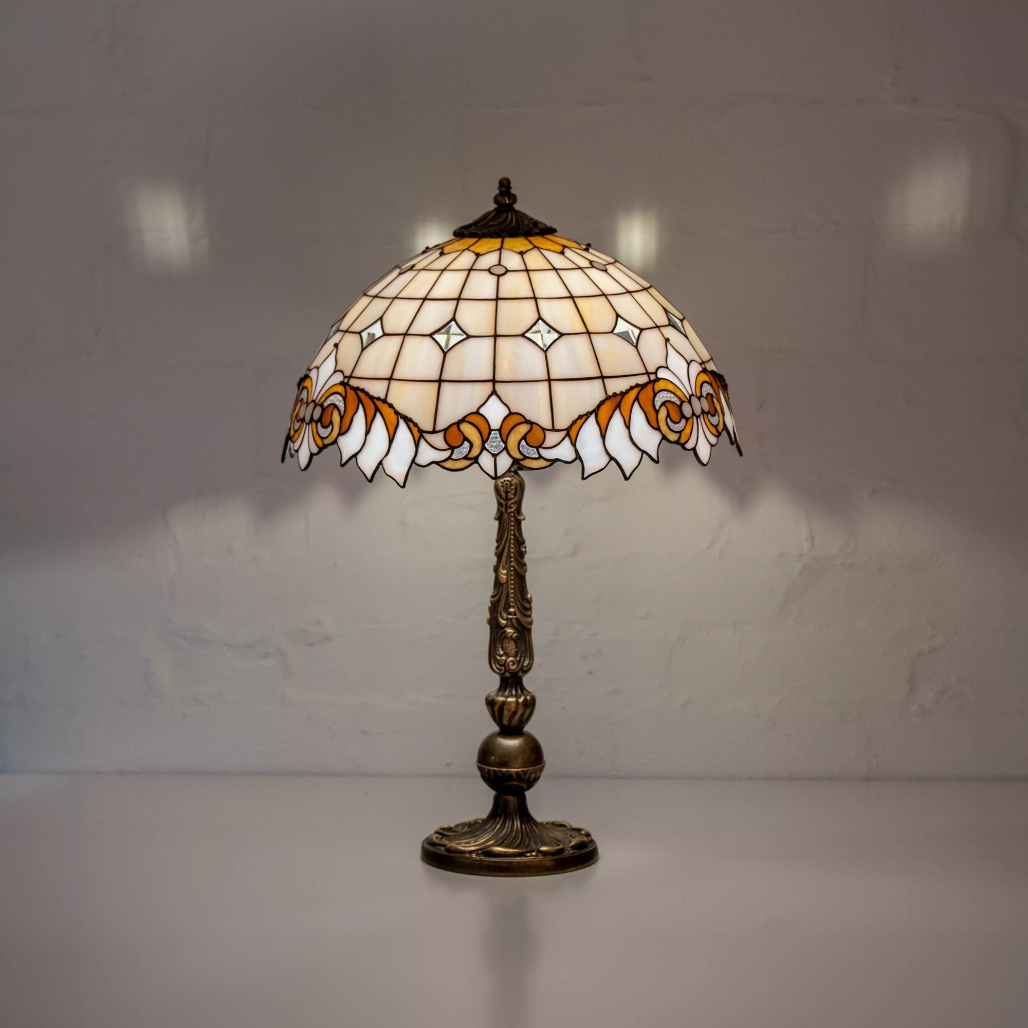 Stained glass table lamp with dome shade glowing softly in a dim interior setting