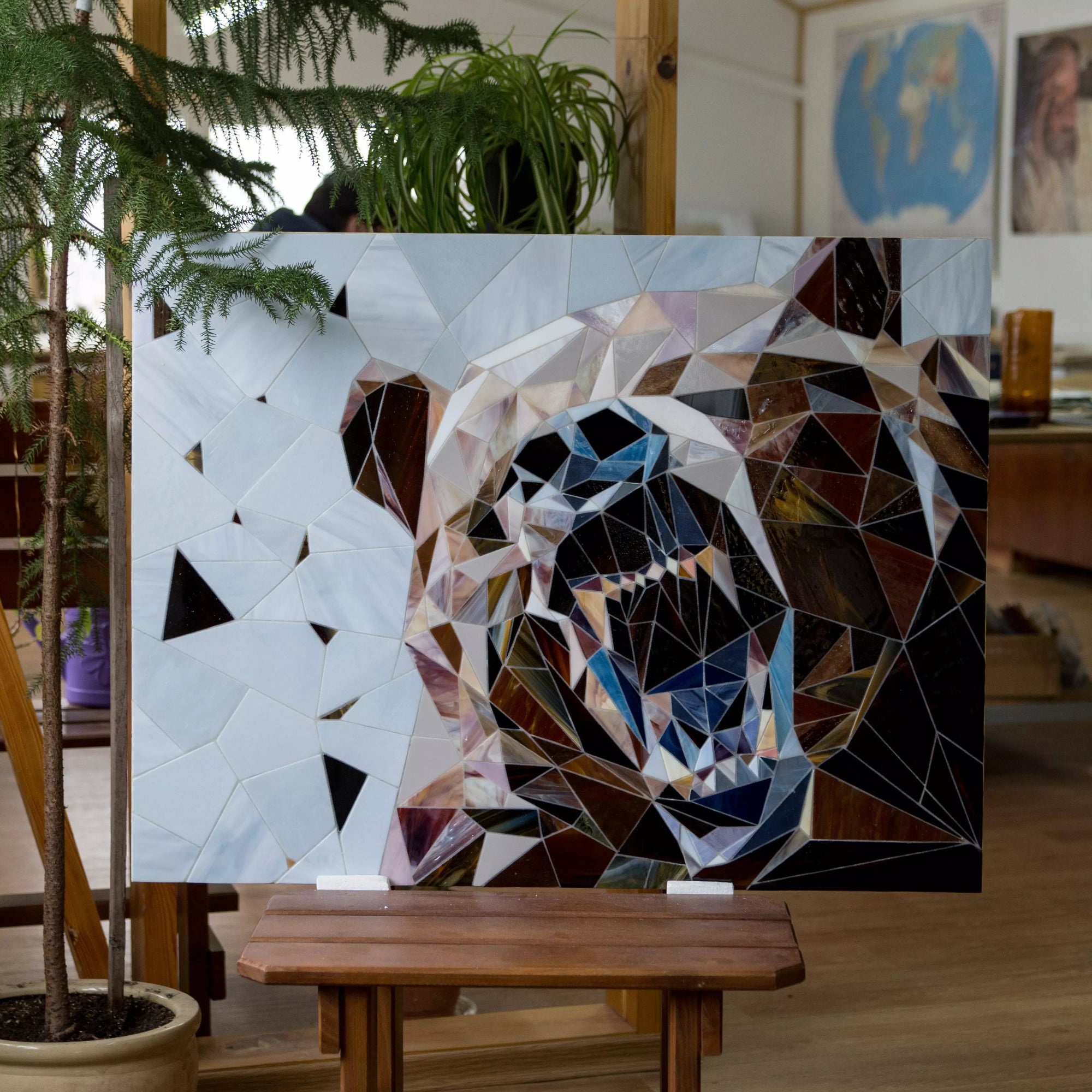 Full view of a polygonal bear mosaic in stained glass on a wooden easel inside an artist’s studio