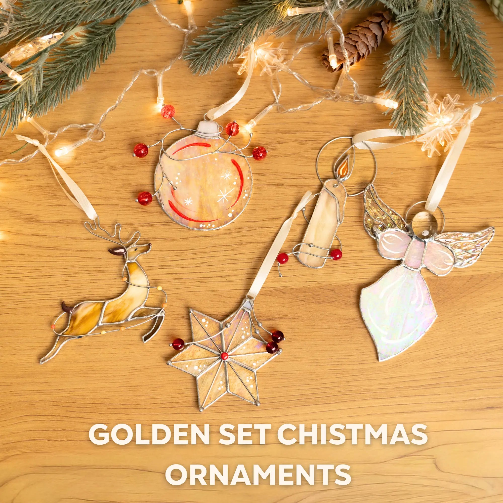 Set of Christmas ornaments including a deer, star, and angel on a wooden surface with lights and pine branches.